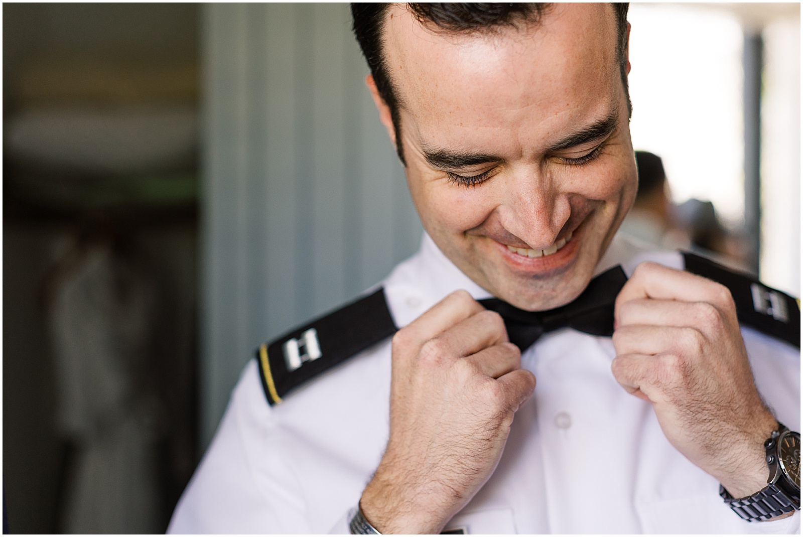 groom smiling while fixing his bowtie for Monterey Wedding Photographer