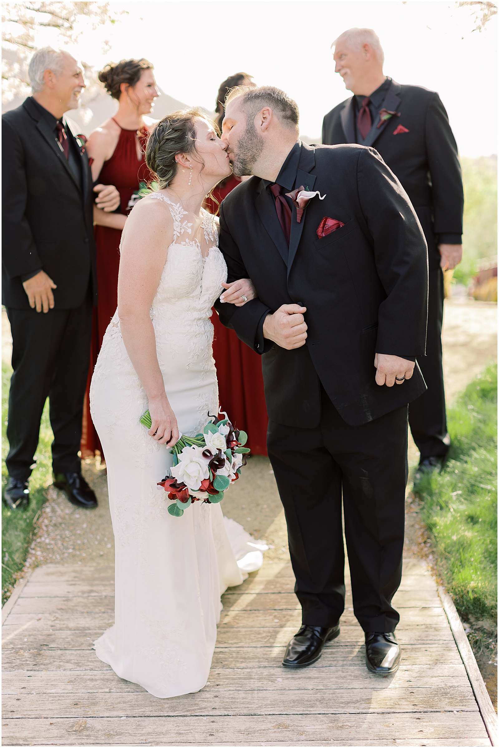 bride and groom kissing with their bridal party in the background