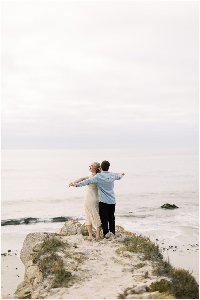 portrait of couple facing ocean raising arms by film photographer AGS Photo Art