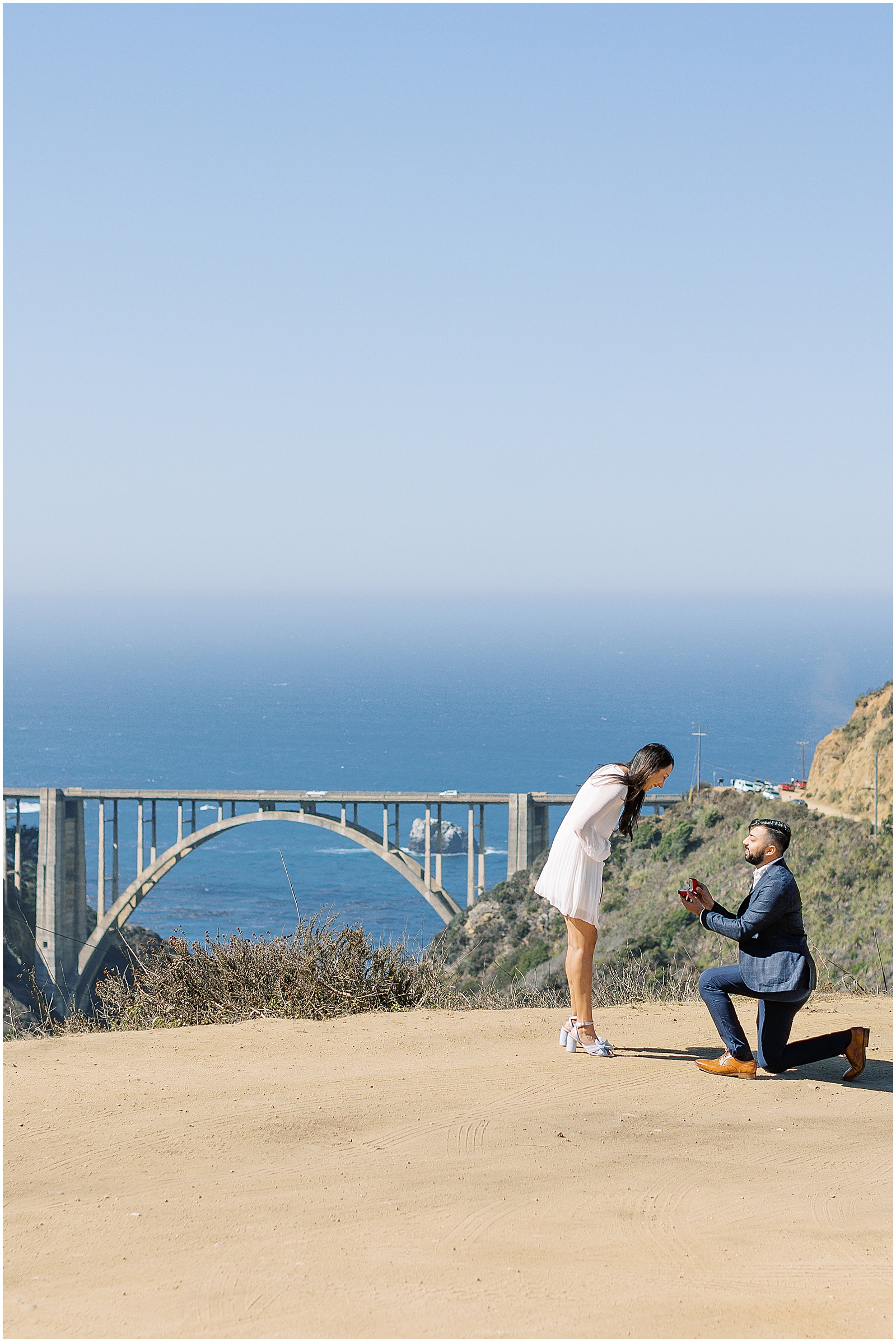 portrait of man kneeling to propose to woman next to bridge by film photographer AGS Photo Art