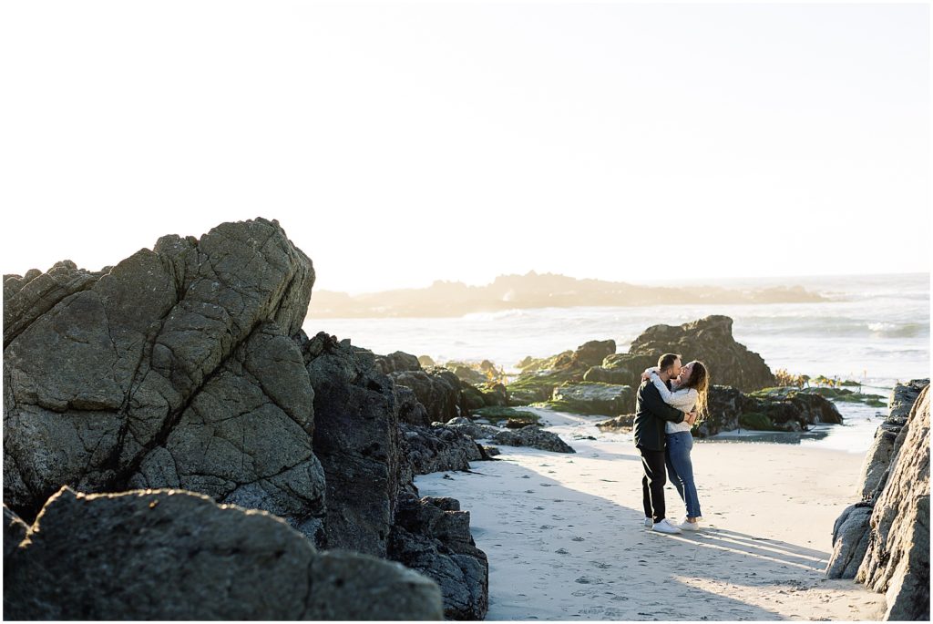 portrait of couple standing next to the ocean along the shore with large rocks surrounding by film photographer AGS Photo Art