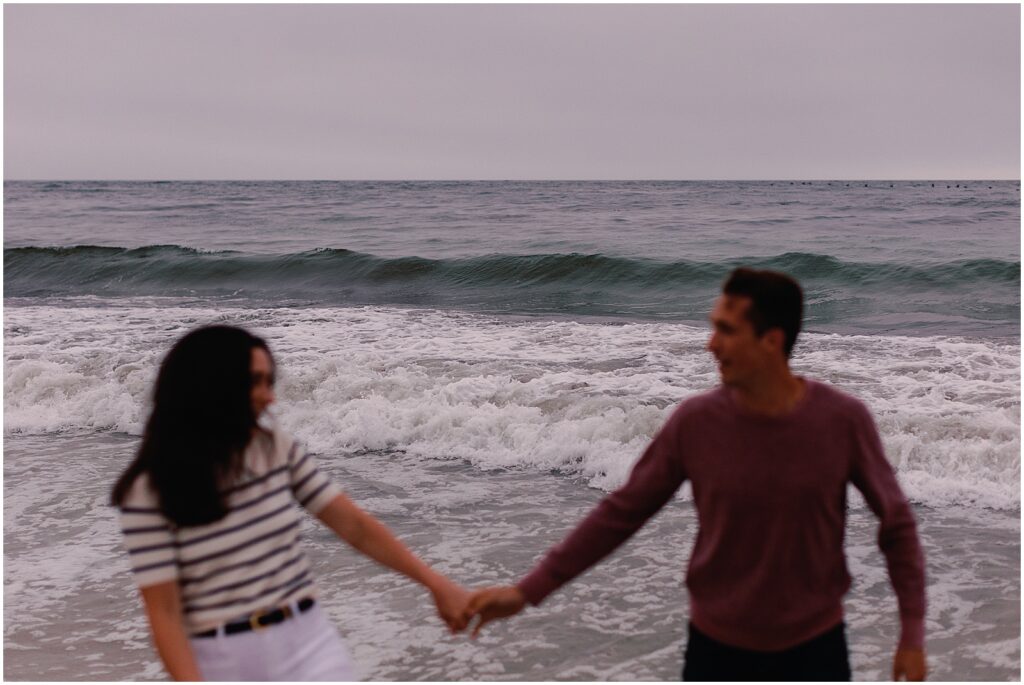 Newly engaged couple holding hands on the beach in Pebble Beach, California. Photography by AGS Photo Art