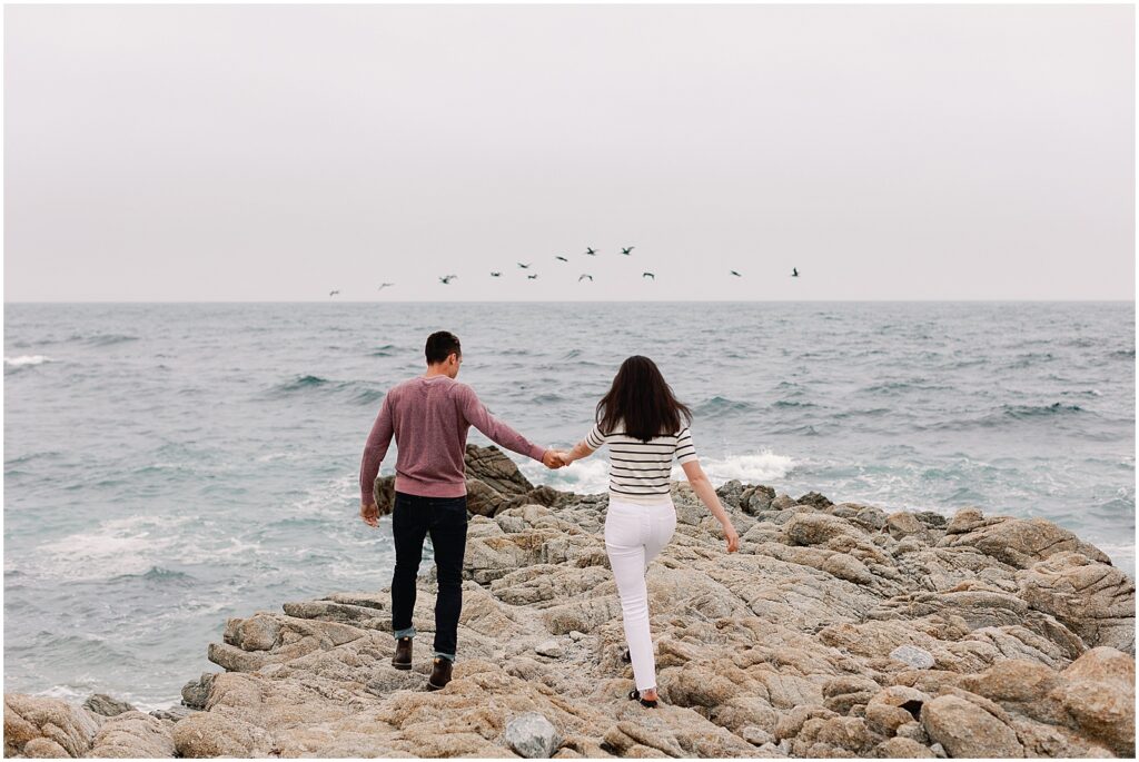 Couple walks along the rocky coast of Pebble Beach for their Engagement photoshoot with AGS Photo Art