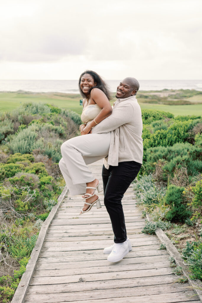 Man picks up his new fiance and twirls her as they both laugh, shot by AGS Photo Art in Pebble Beach, California.