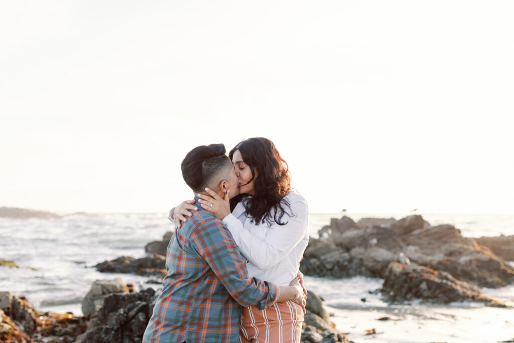 Adventure engagement photography with kissing LGBTQ couple on the coast.