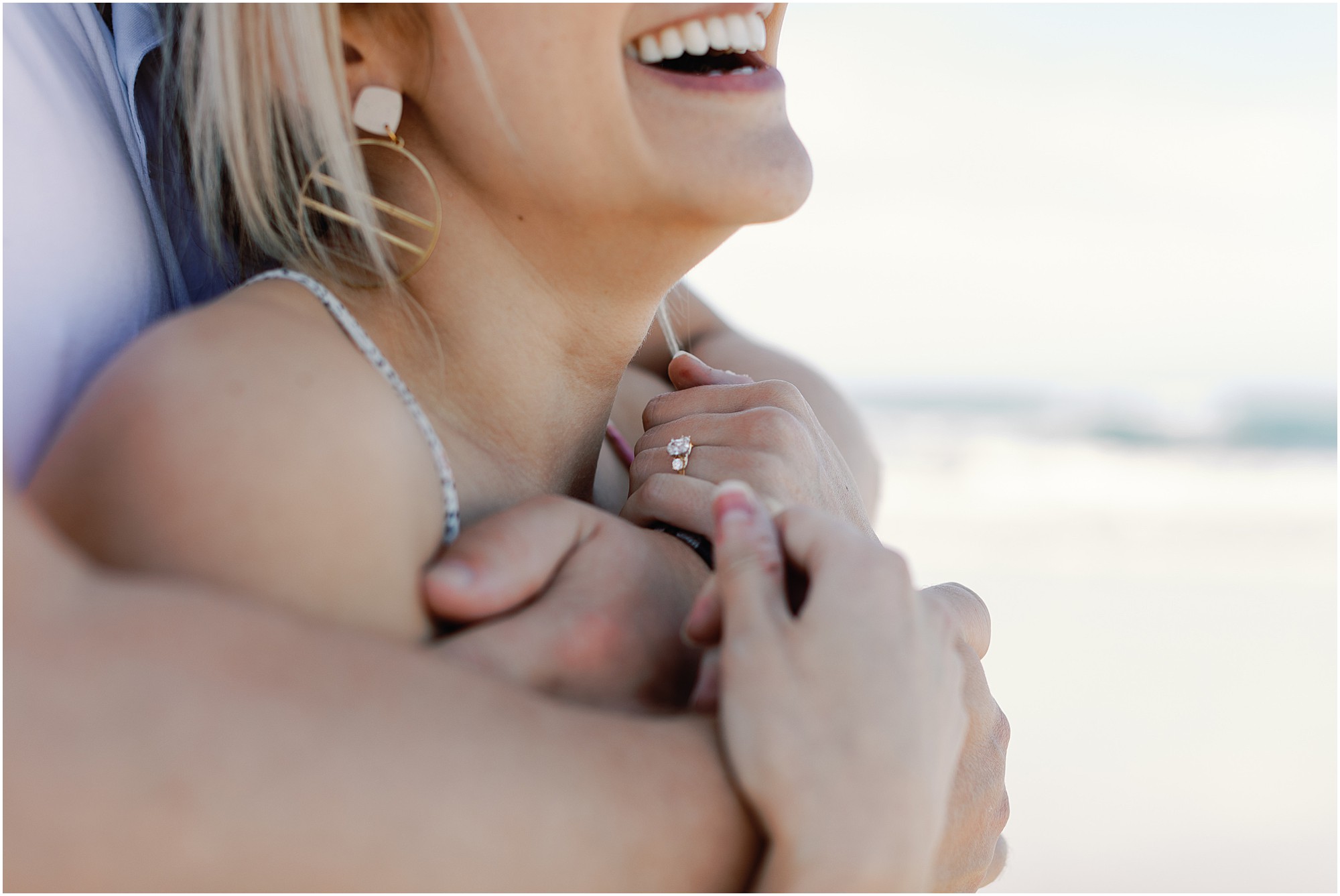 Close-up of Tasha’s engagement ring as she laughs in Josh’s arms during their Asilomar Beach proposal.
