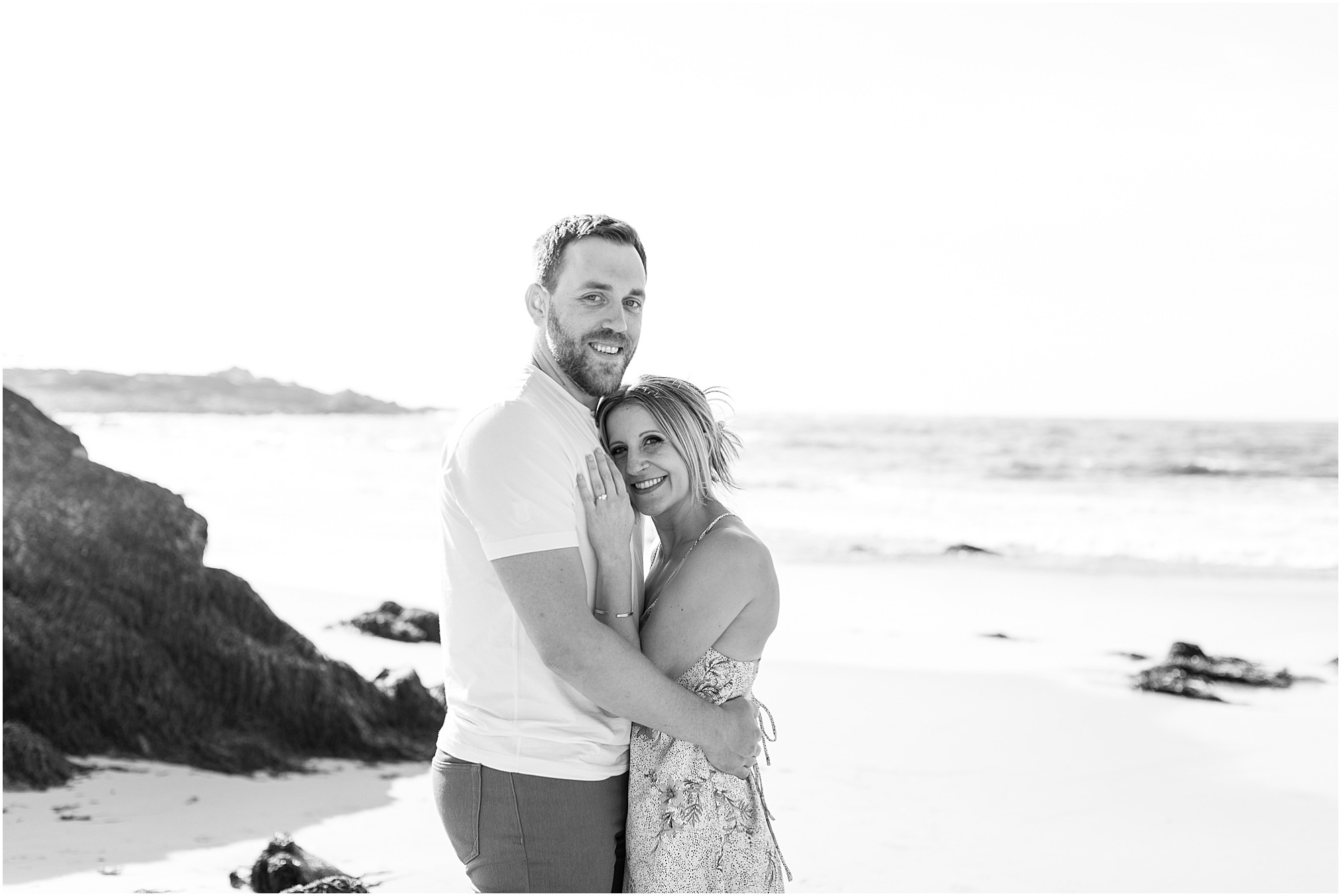 Black and white photo of Josh and Tasha smiling on the beach after their proposal, captured by Asilomar Beach Proposal Photographer.