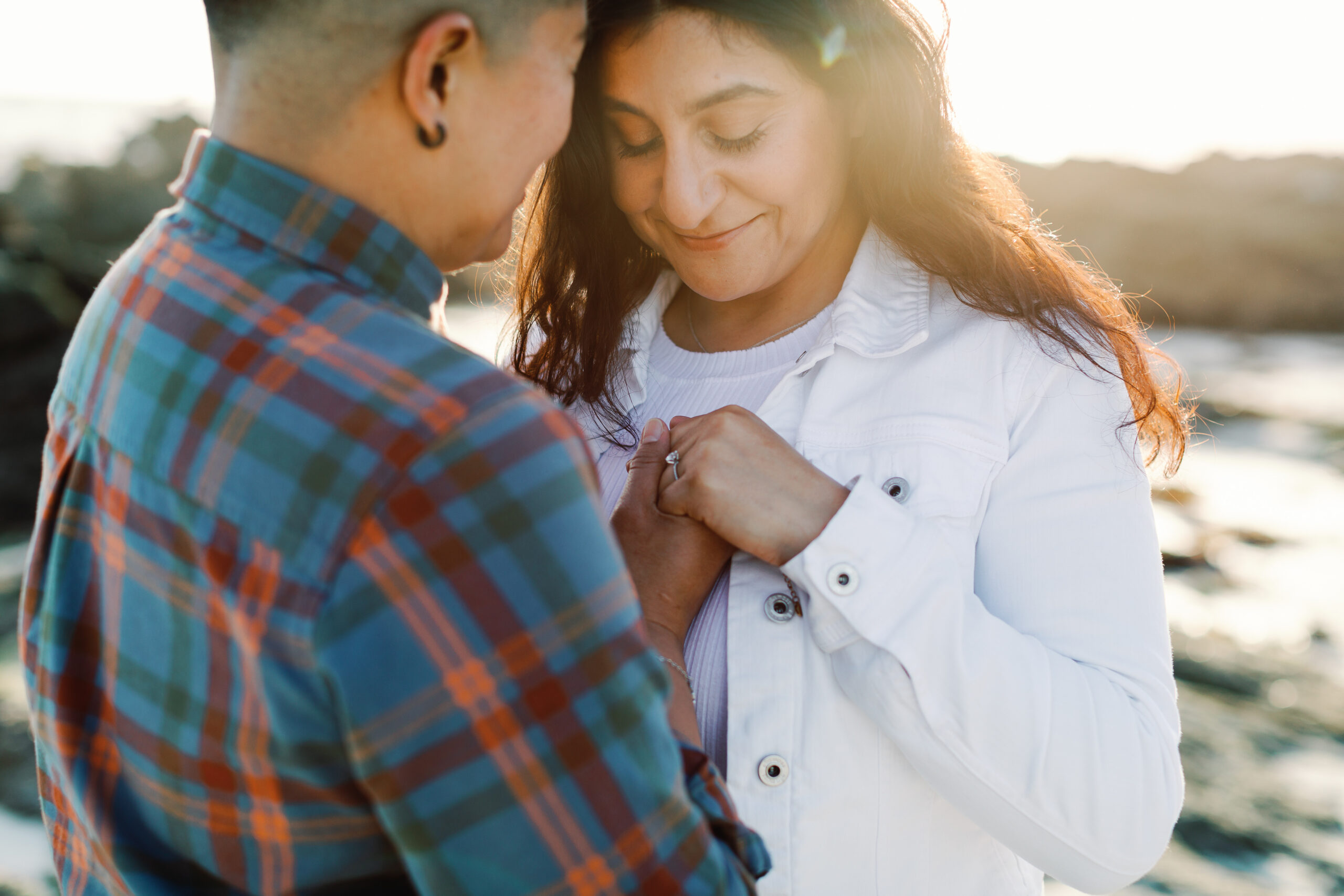 Couple embracing on the Carmel coastline during adventure engagement session.