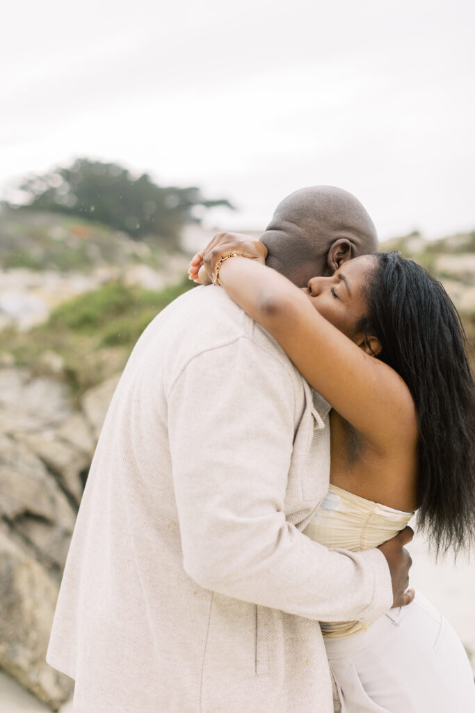 Couple hugging on the Spanish Bay coastline during engagement photography.