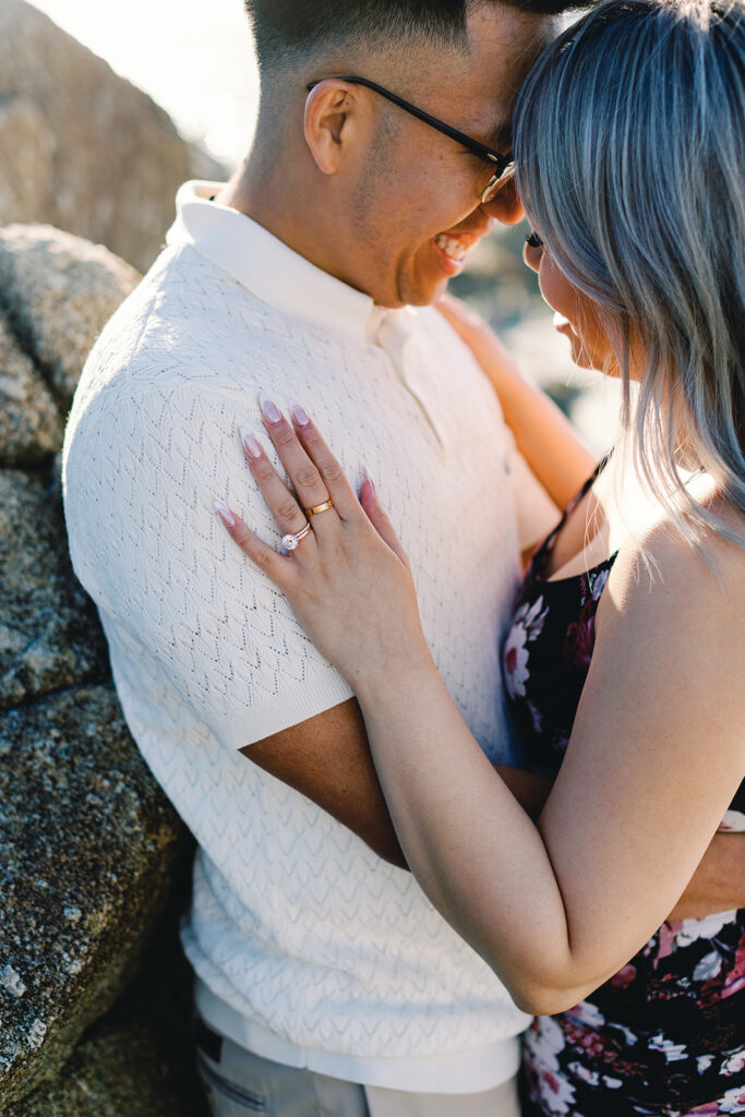 Close-up of Vivian’s engagement ring resting on Mark’s shoulder as they share a forehead-to-forehead laugh during their Pebble Beach engagement session.
