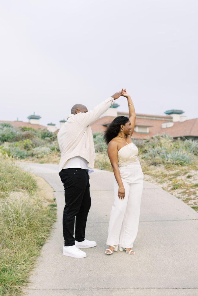 Couple dancing on the Spanish Bay coastline during engagement photography.