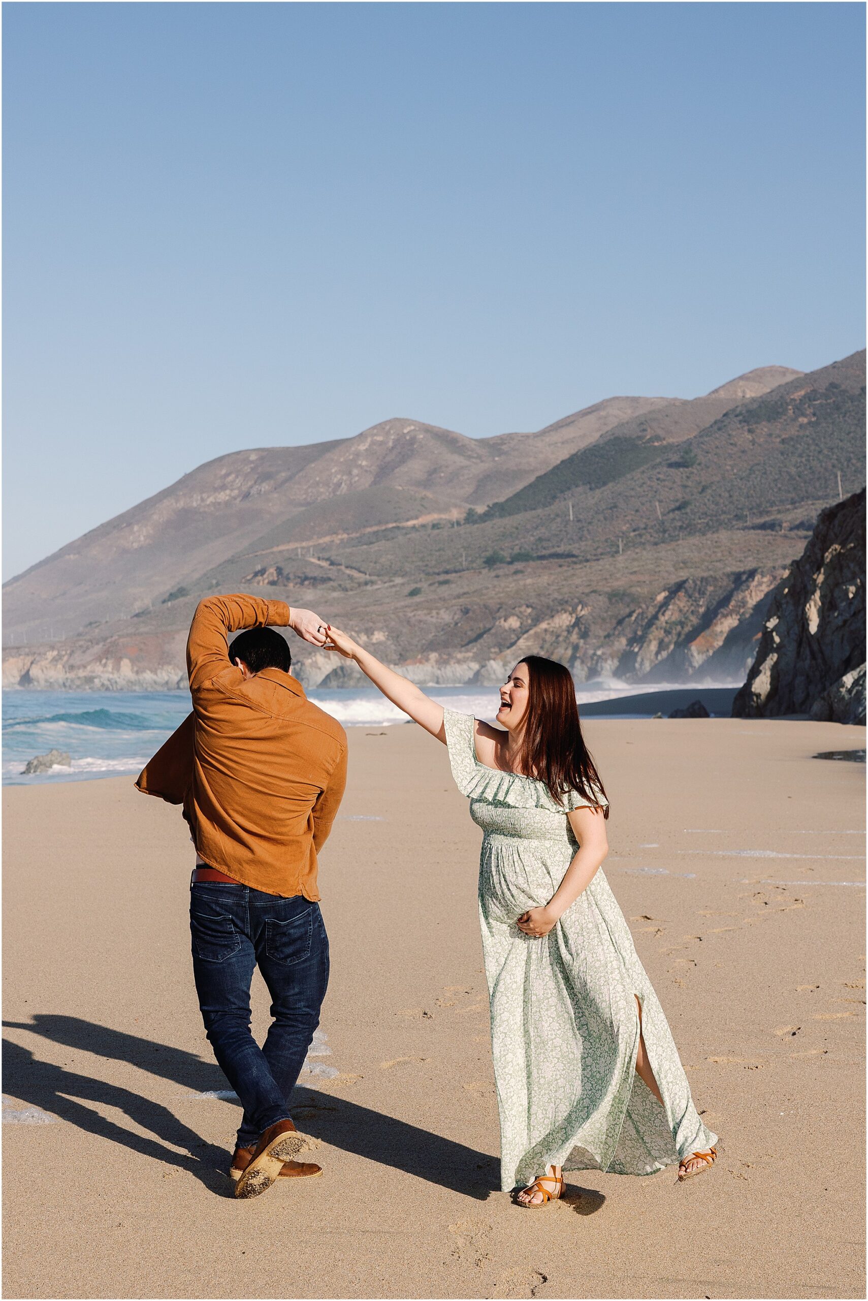 Amanda and Cory laugh and dance together during their joyful Big Sur maternity session.