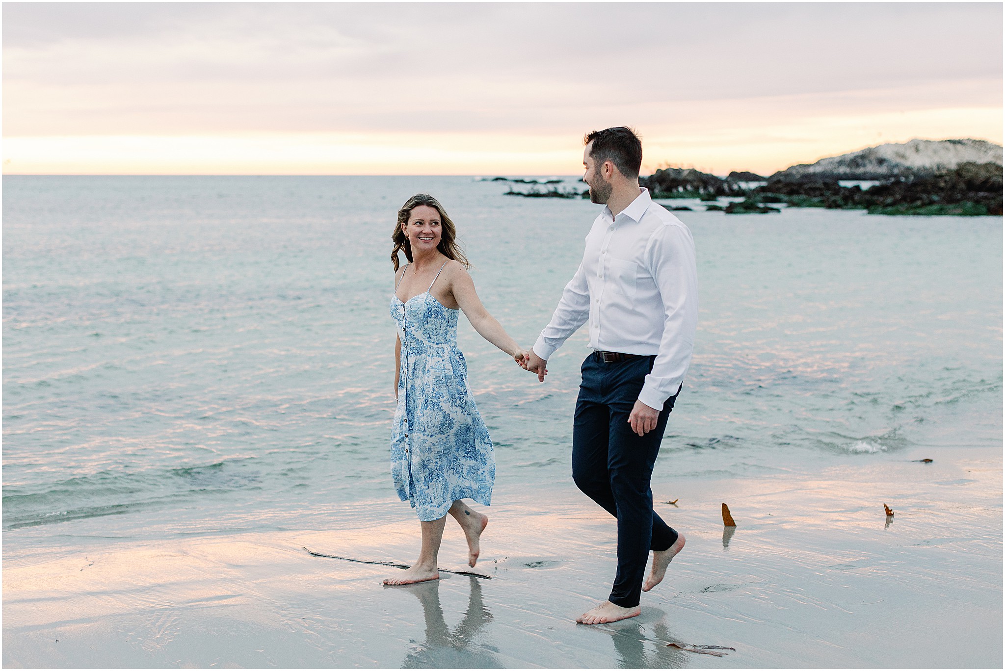 Couple walking hand in hand along Pebble Beach after proposal.