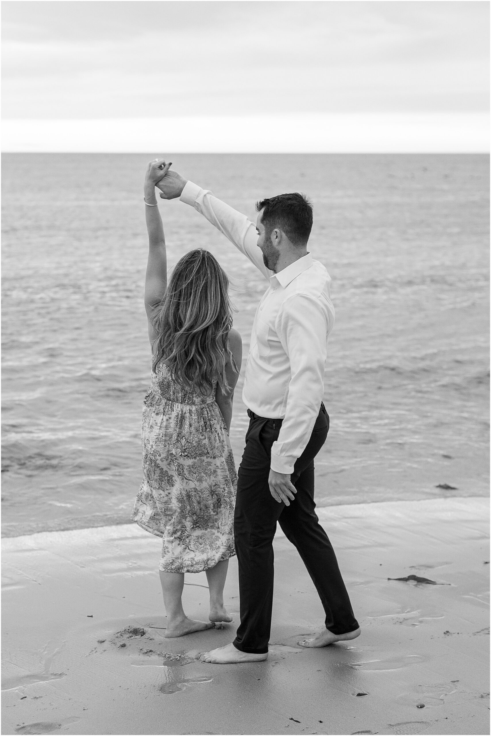 Happy engaged couple dancing along Pebble Beach after saying yes.