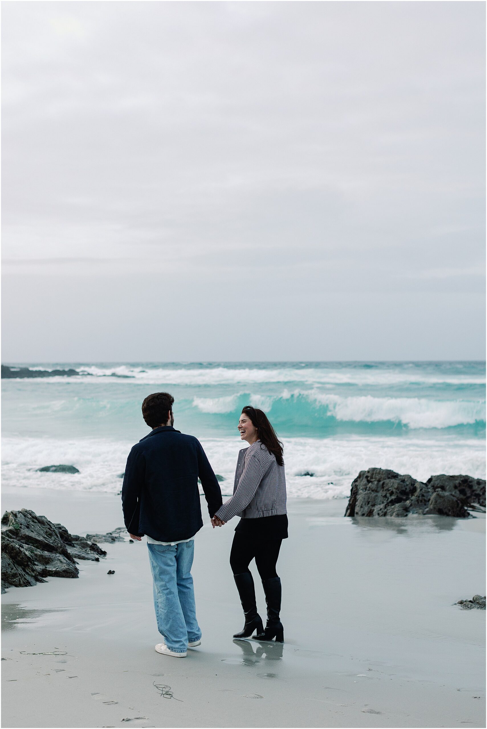 Couple walking hand in hand along Pebble Beach.