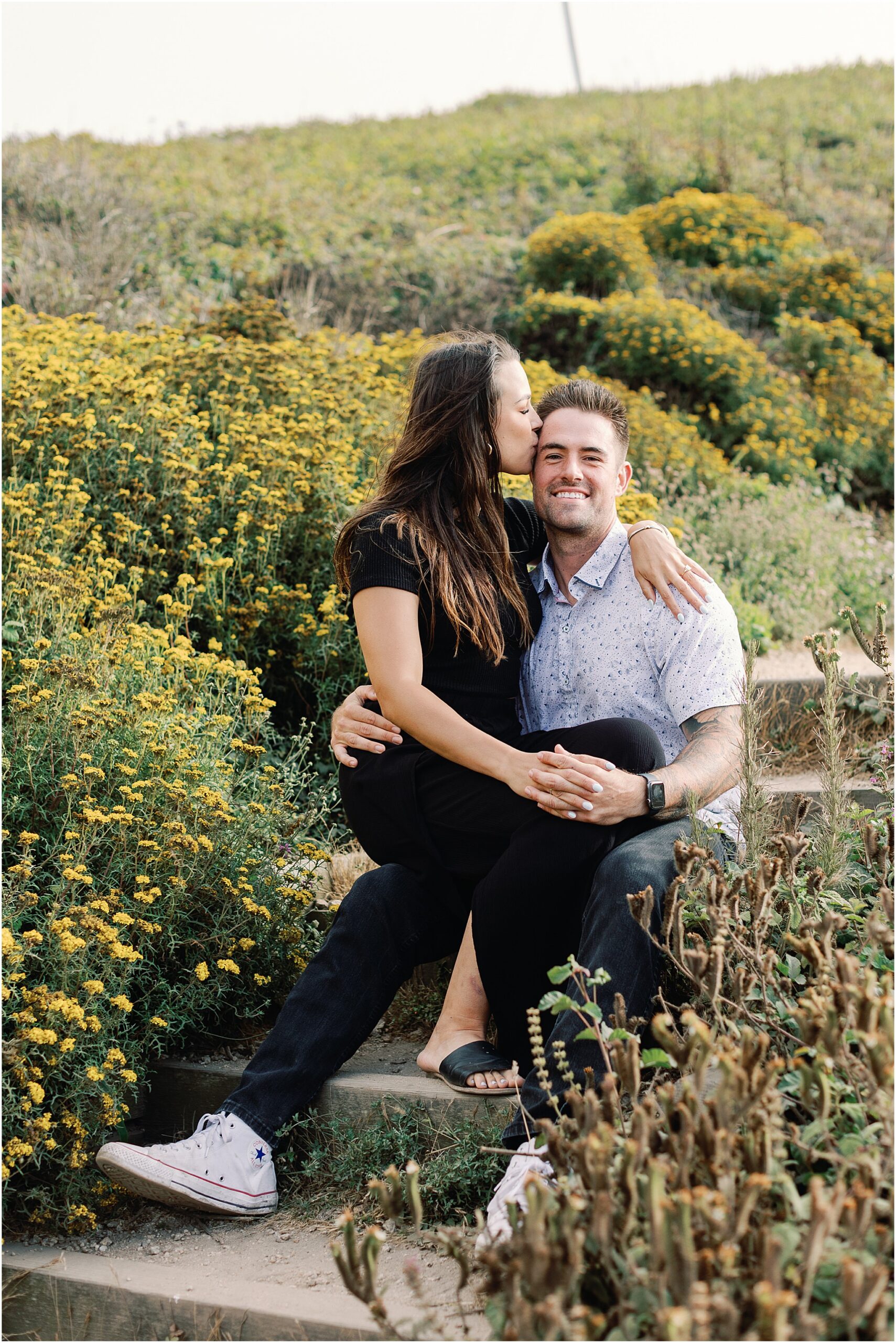 Marc and Lauren surrounded by coastal wildflowers during their Big Sur engagement photos.