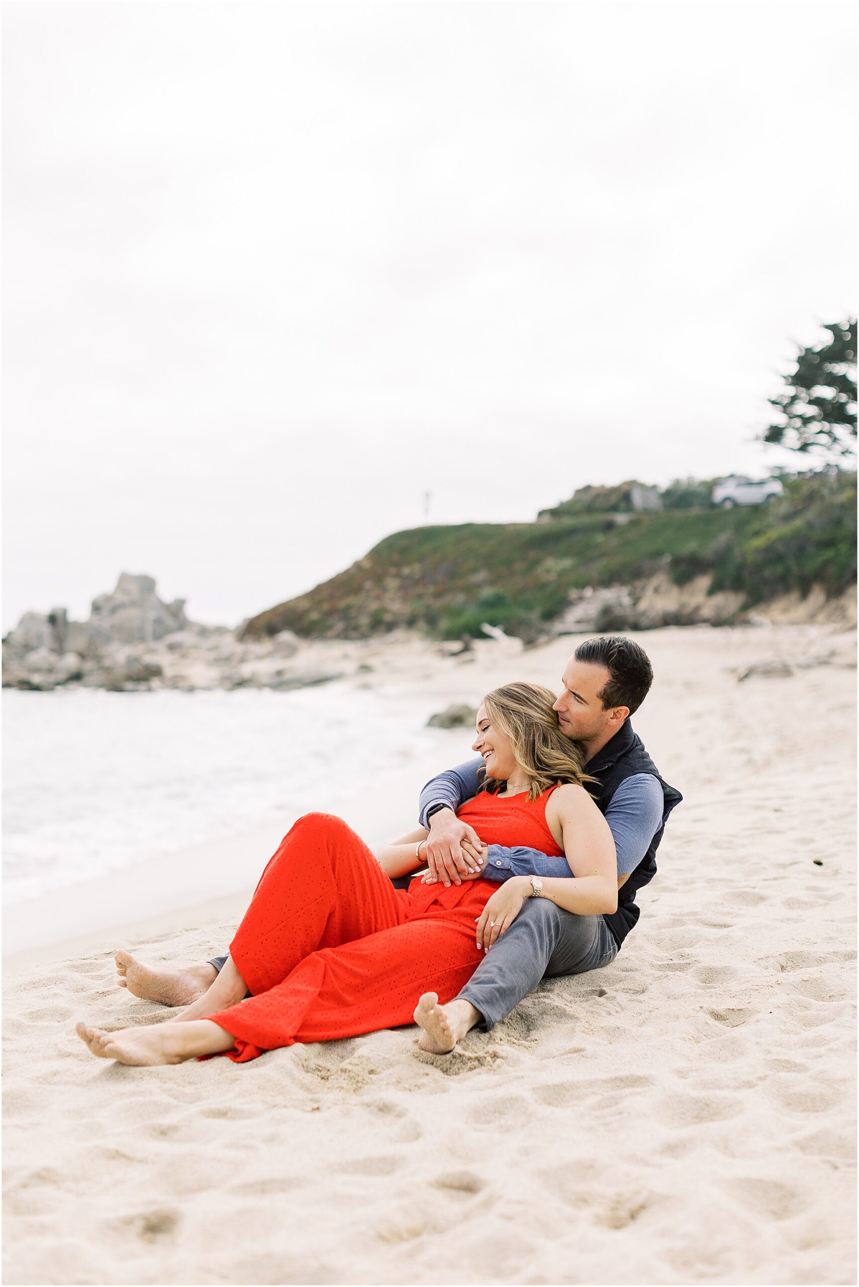 Chaplin and Nasim sitting together on the sand at Carmel River Beach.