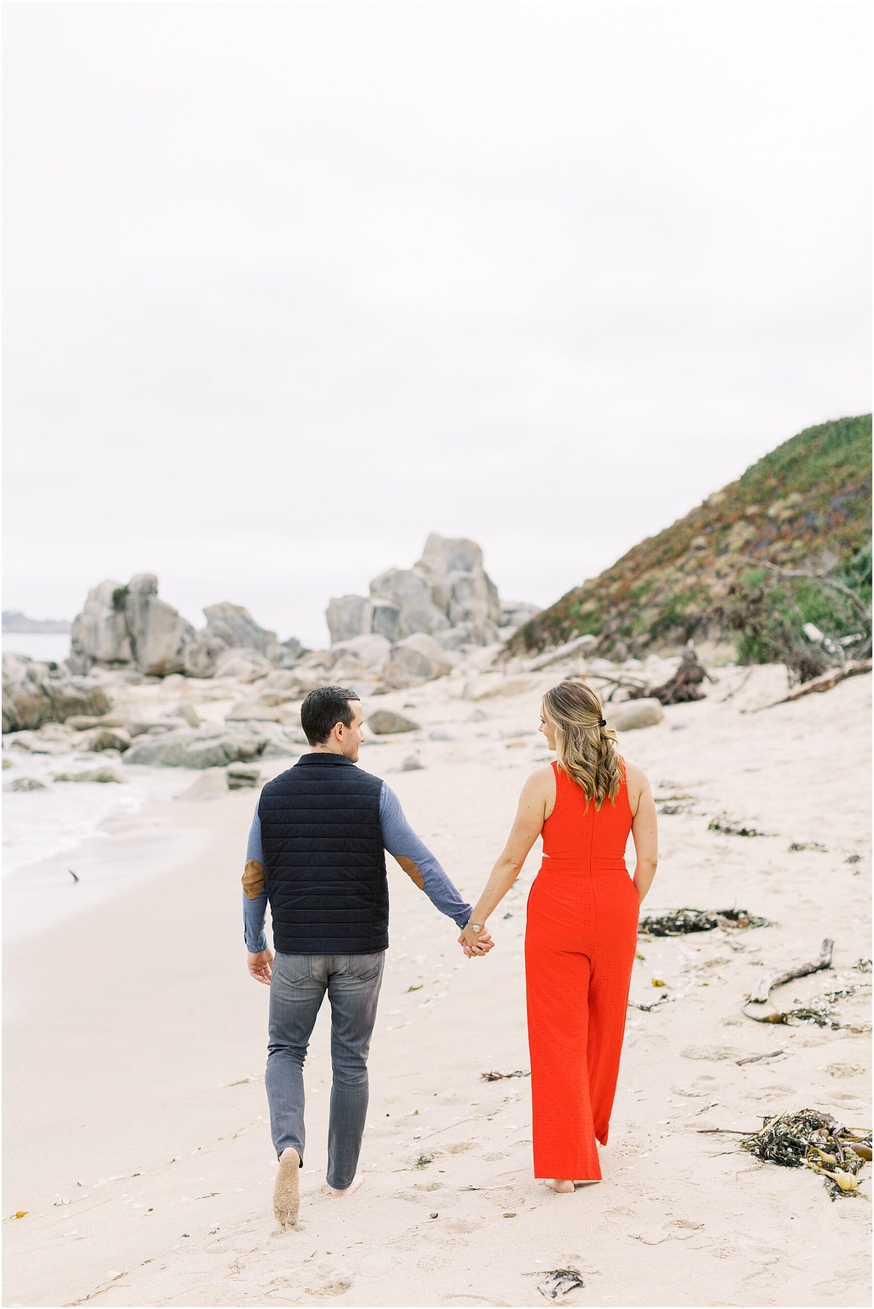 Chaplin and Nasim walking away from the camera along the wet sand at sunset