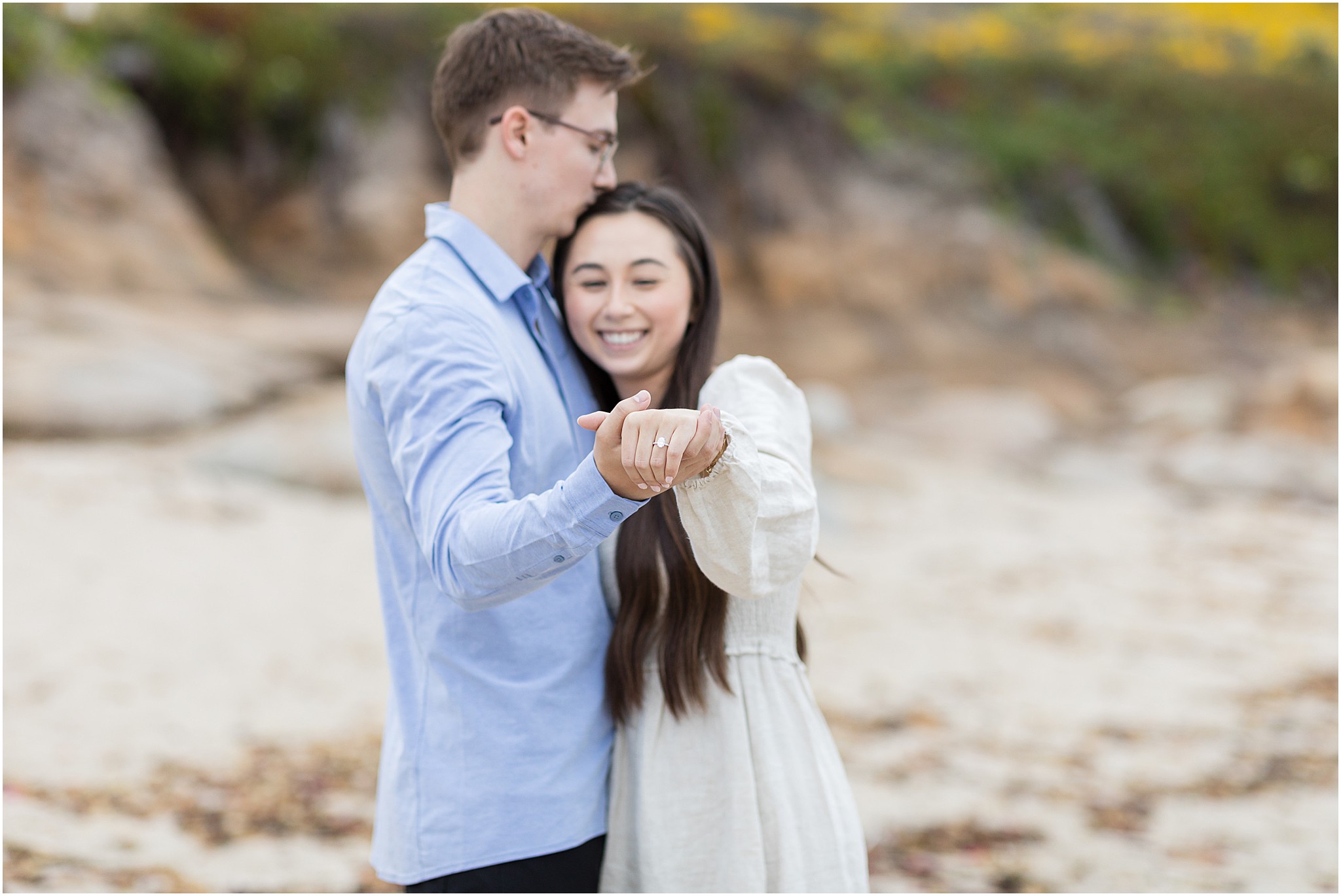 Couple laughing together with a close up of the ring on the rocky shoreline during their Carmel State Beach proposal.