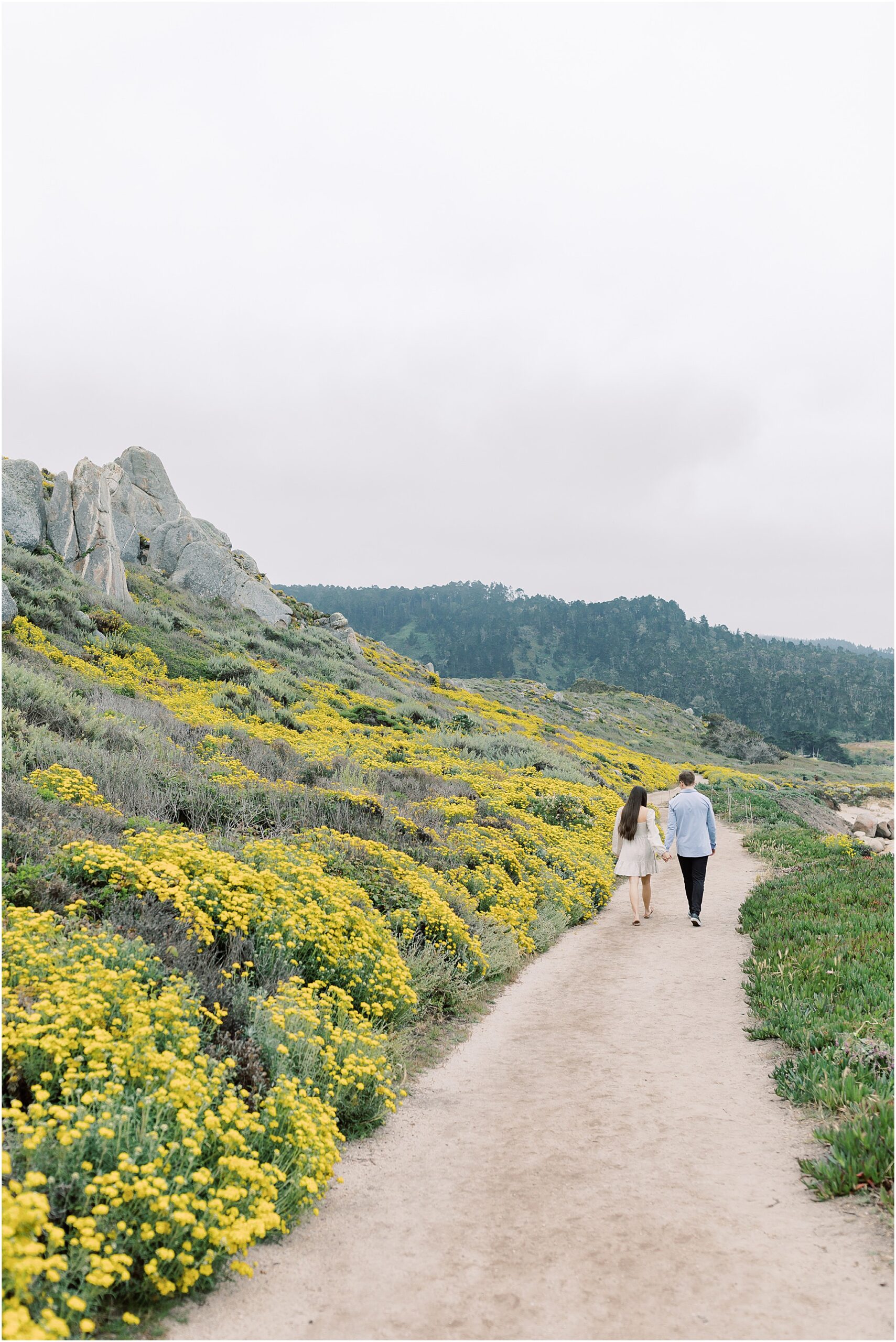 Zach and Shannon walking hand in hand along Carmel State Beach at sunset.