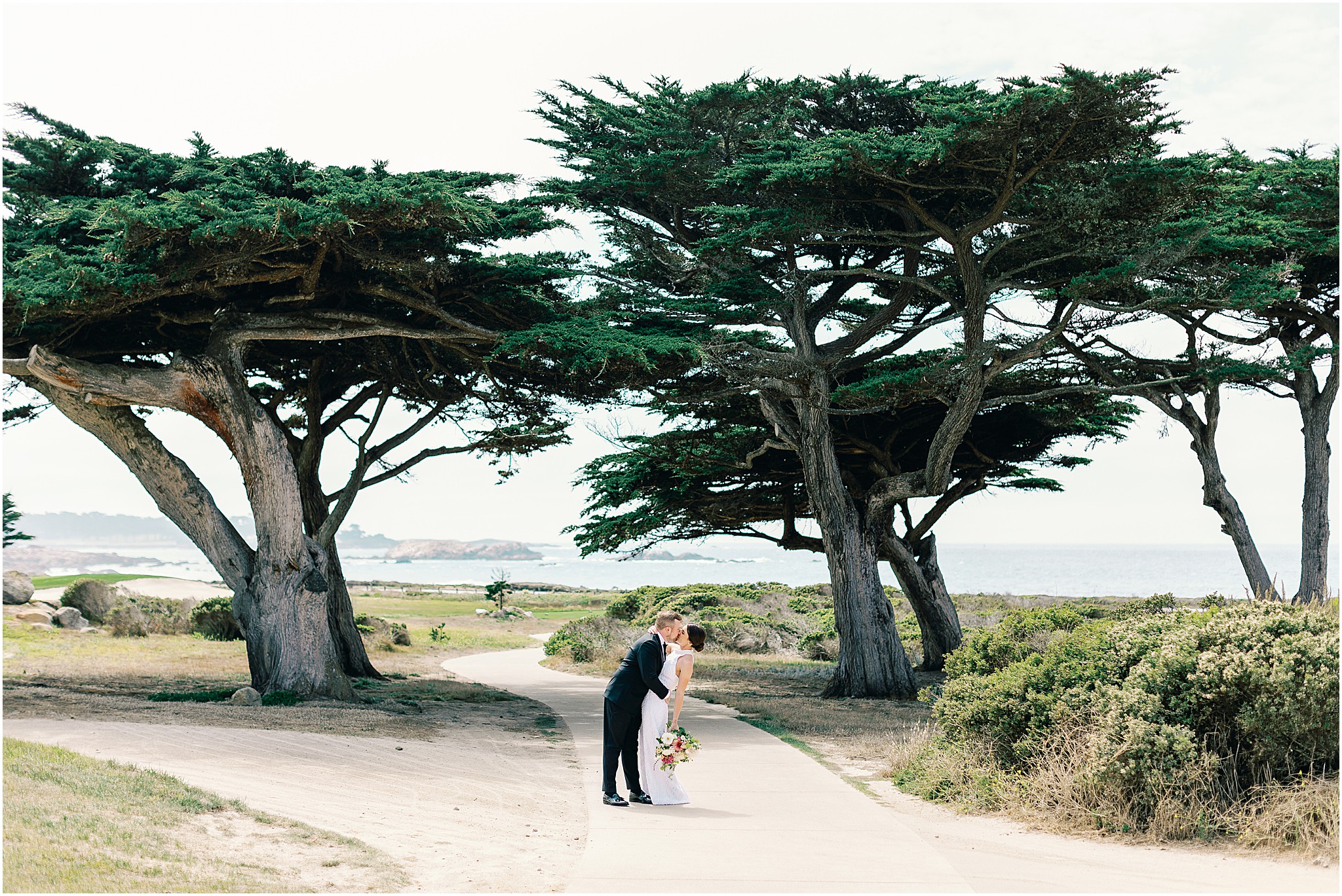 Couple’s emotional kiss among coastal cypress trees.