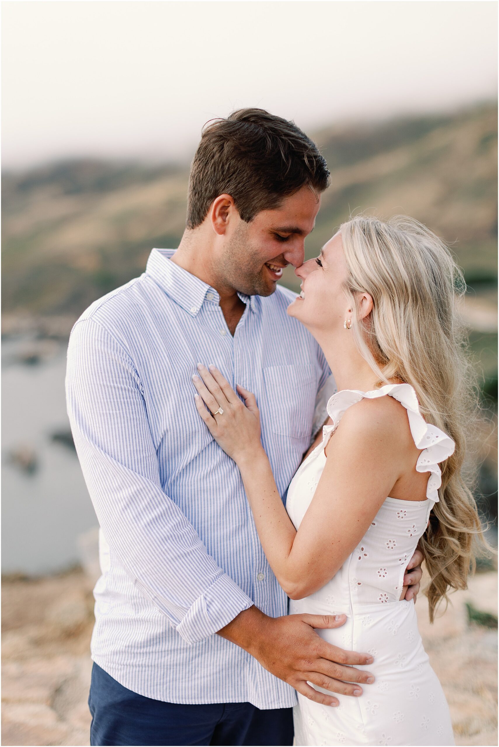 Couple hugging tightly after getting engaged on the coastline