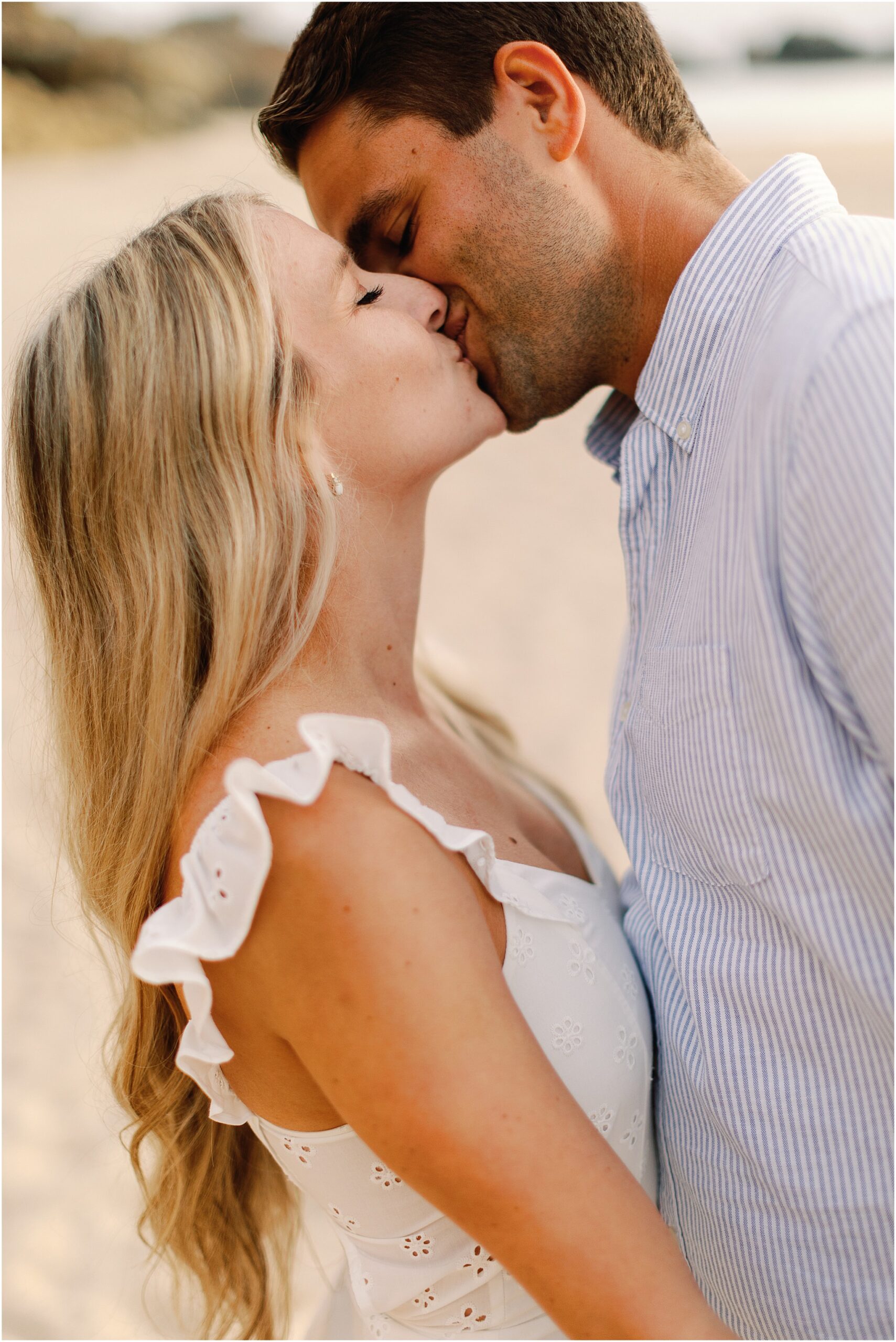Newly engaged couple kissing after proposal on the California coast