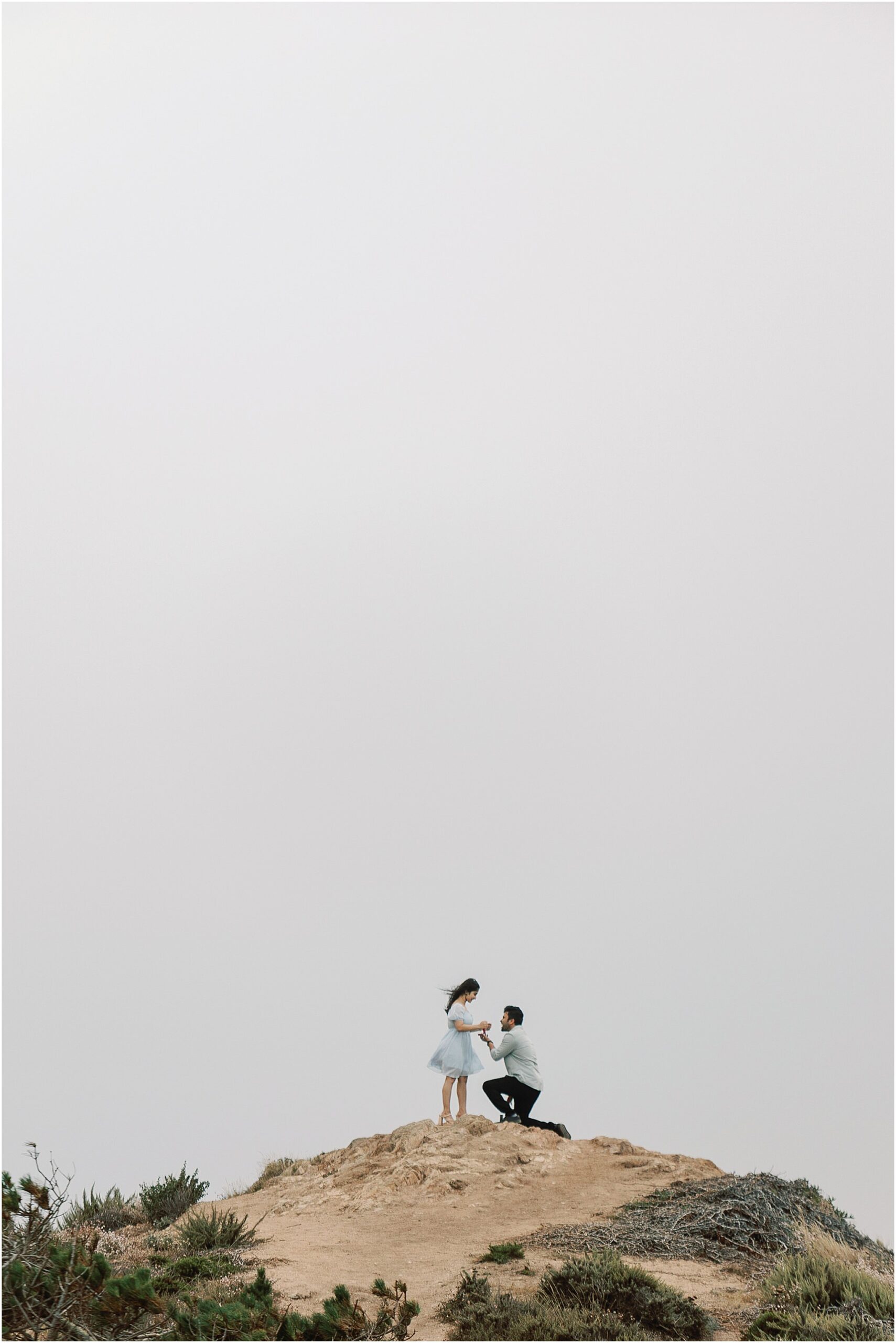 Proposal photo of groom on one knee as he asks her to marry him on the Big Sur coastline.