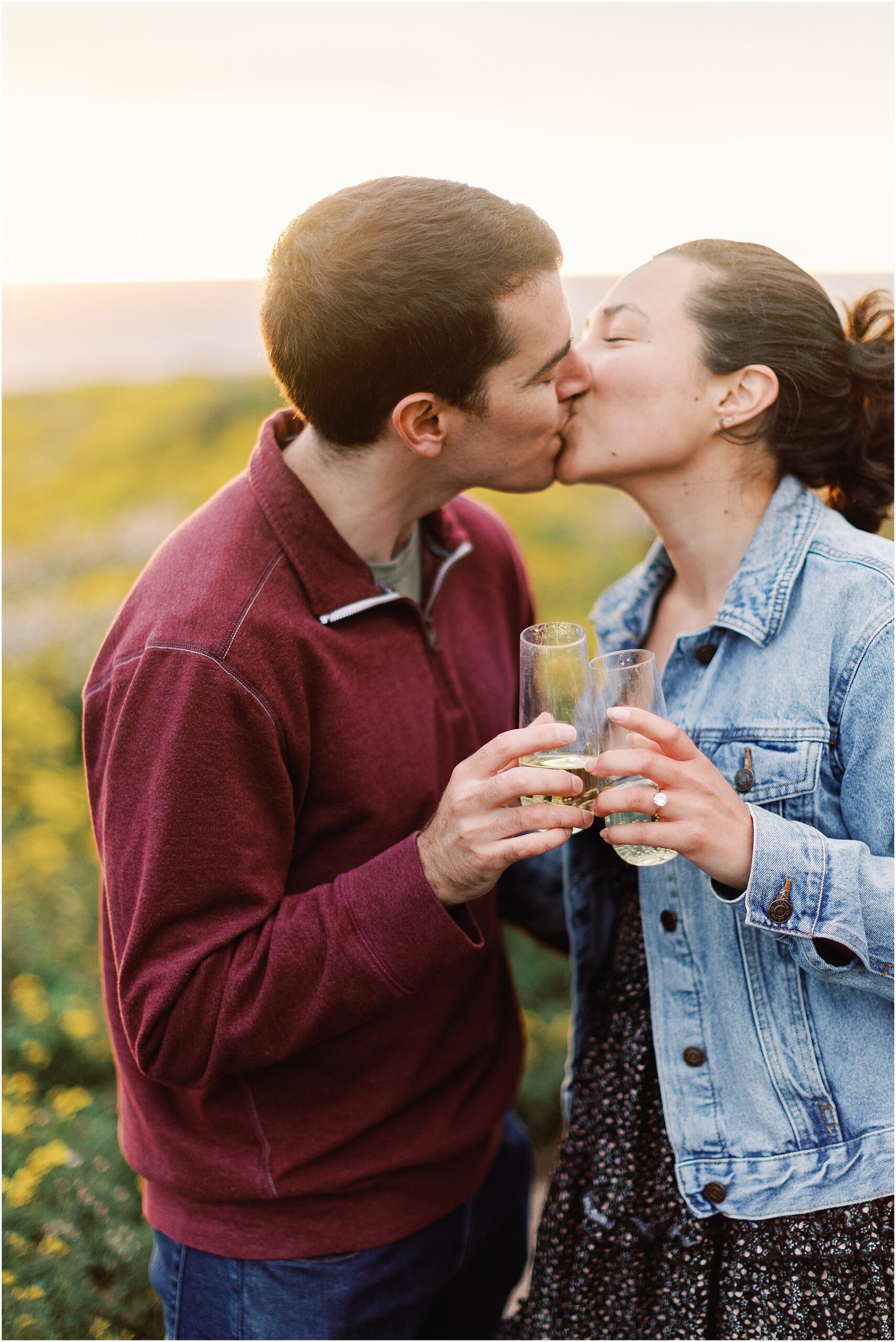 Ron and Anna sharing a champagne toast and kiss after their Big Sur sunset proposal.