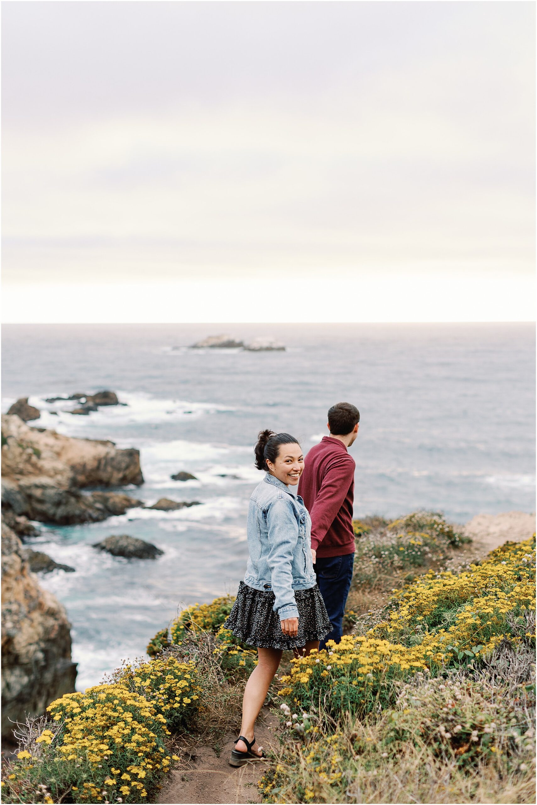 Ron and Anna walking hand in hand along a coastal path in Big Sur.
