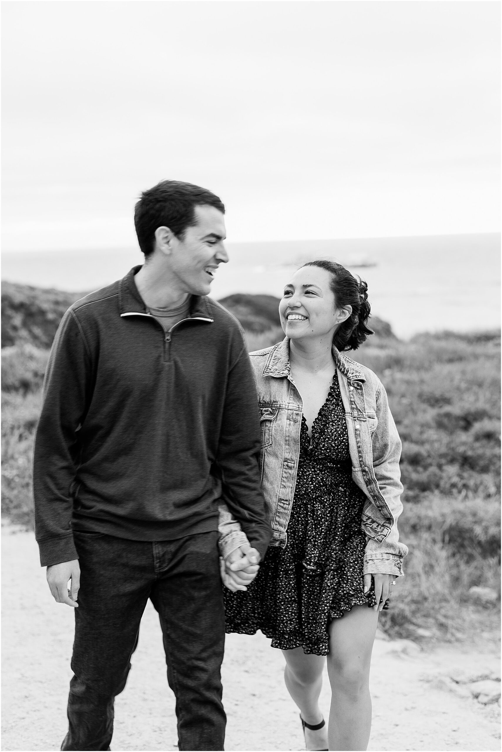 Anna looking at Ron with ocean views behind them on the Big Sur coastline photographed in black and white.