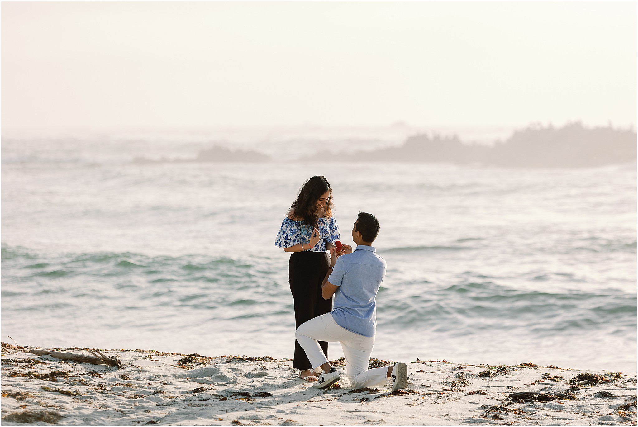 Beach proposal in Carmel California with him on one knee and her reacting joyfully