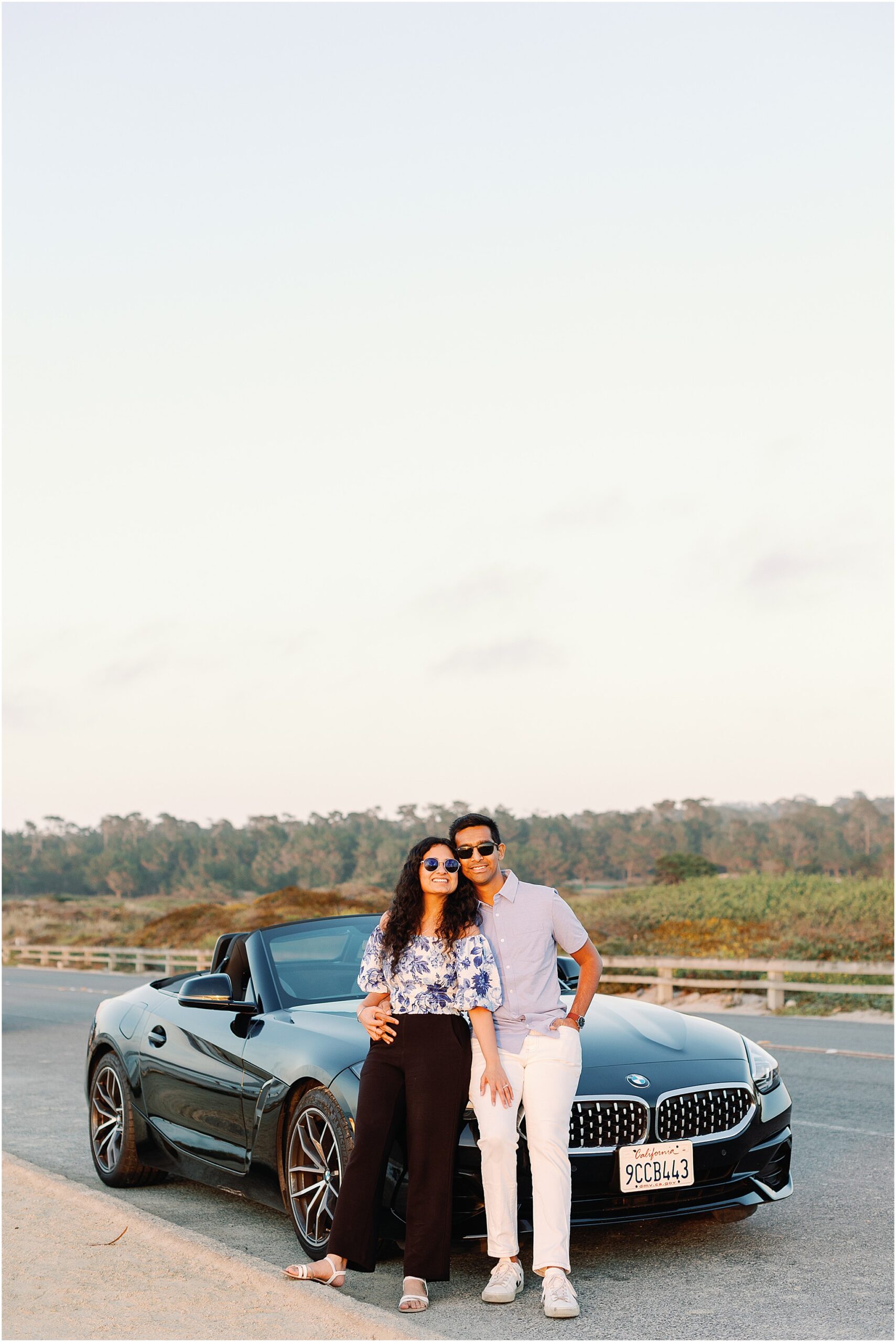 Couple leaning together on a car before heading to Carmel Beach at sunset