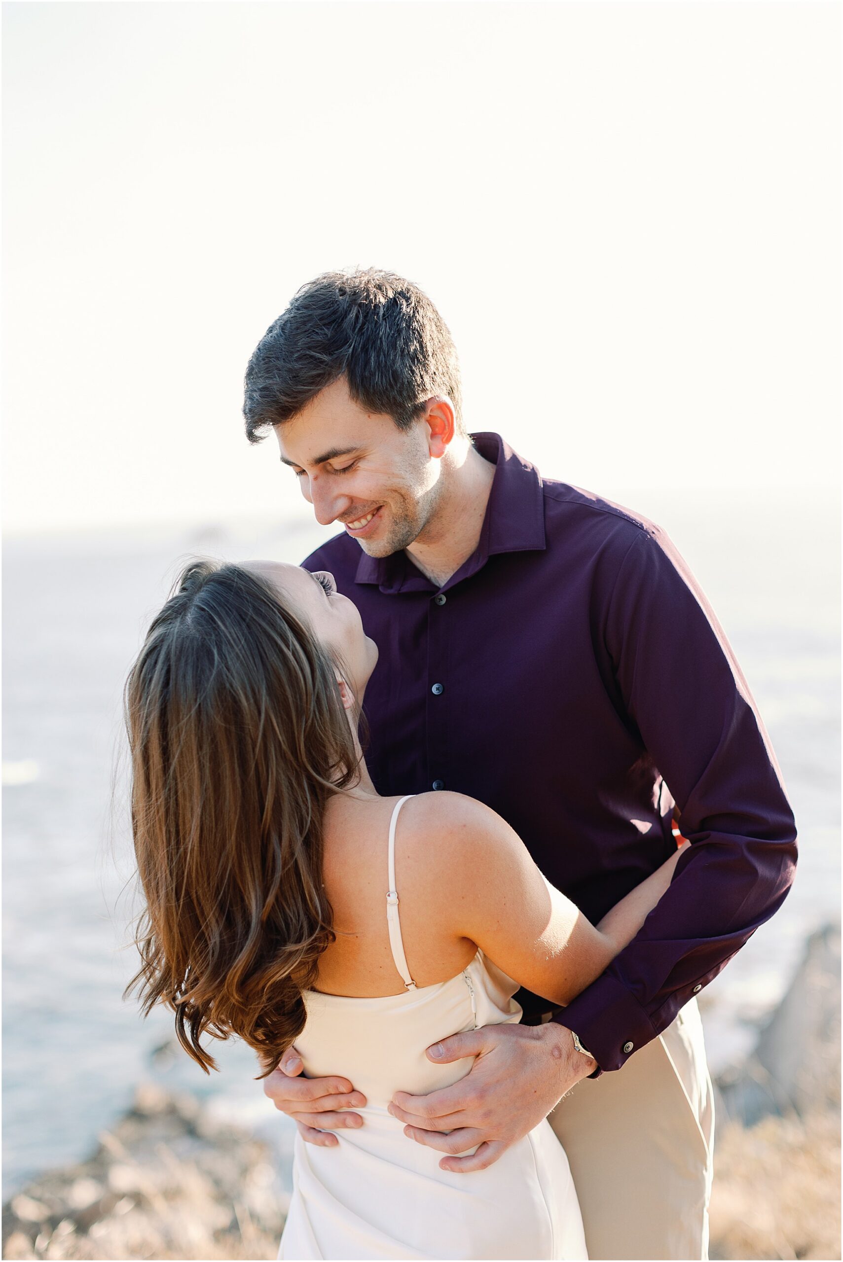 Joey smiling at Jenny during their romantic coastal engagement photos