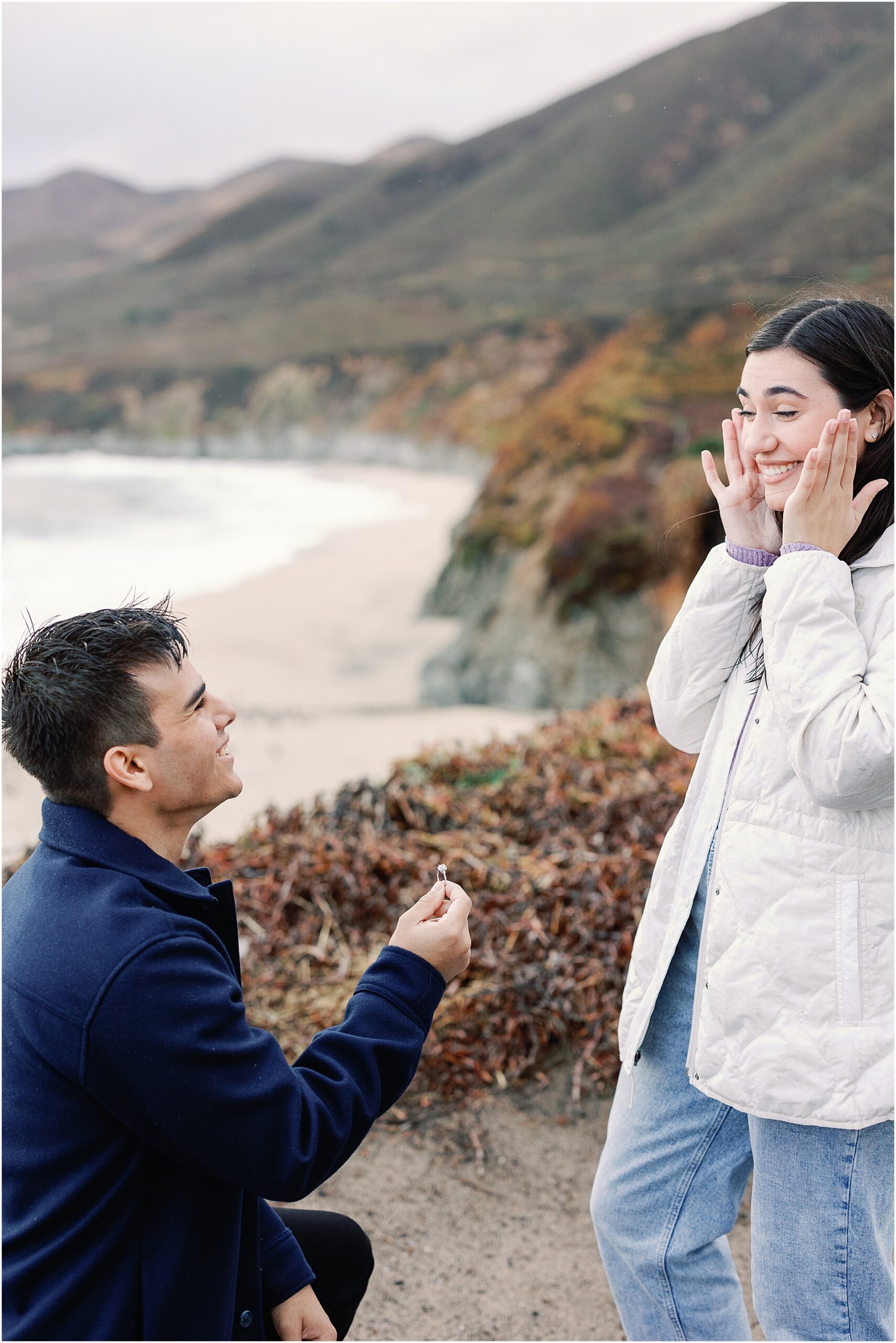 Erica reacting with joy during Big Sur proposal on a cliff.