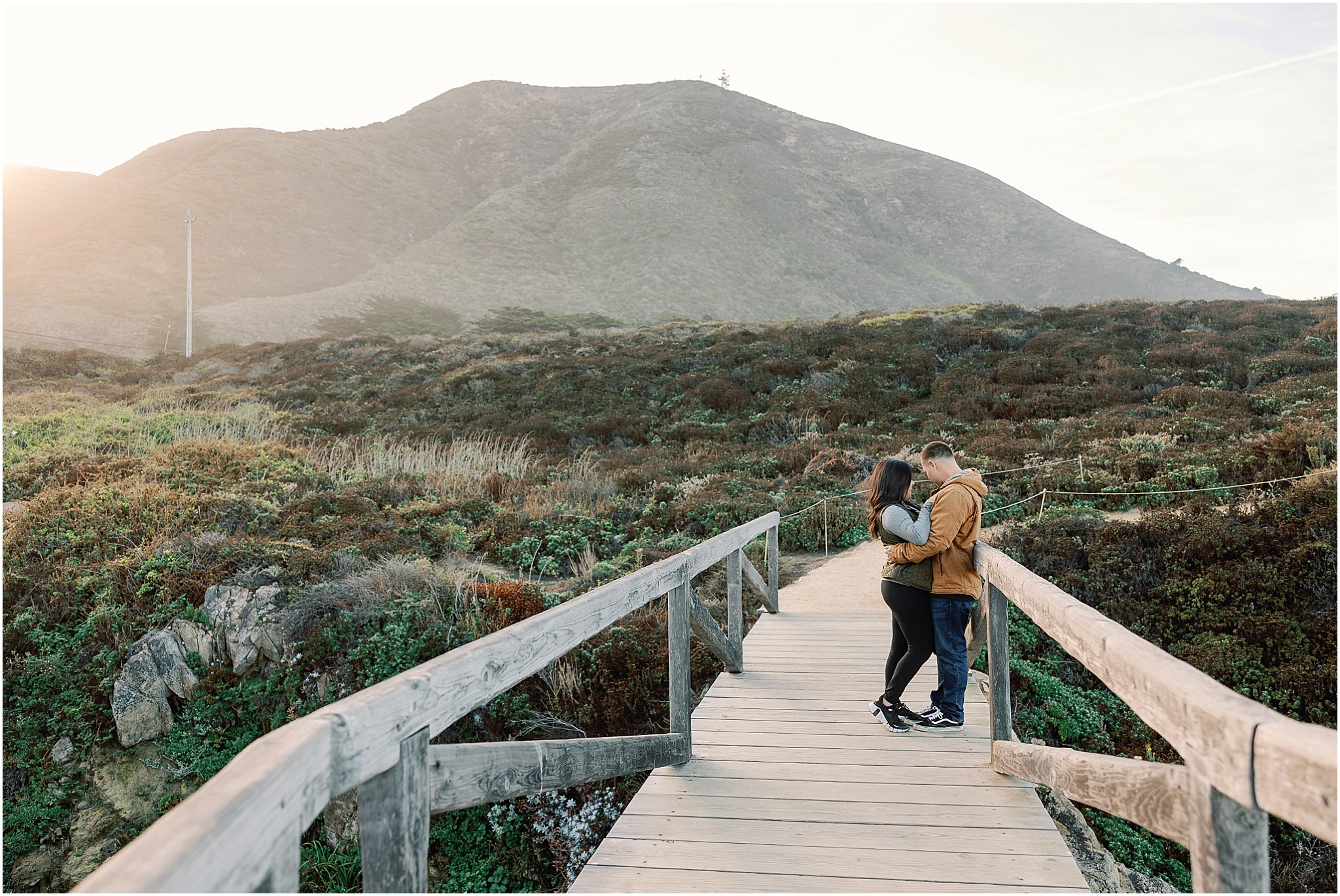 Couple embracing along cliffside trail in Big Sur before proposal.