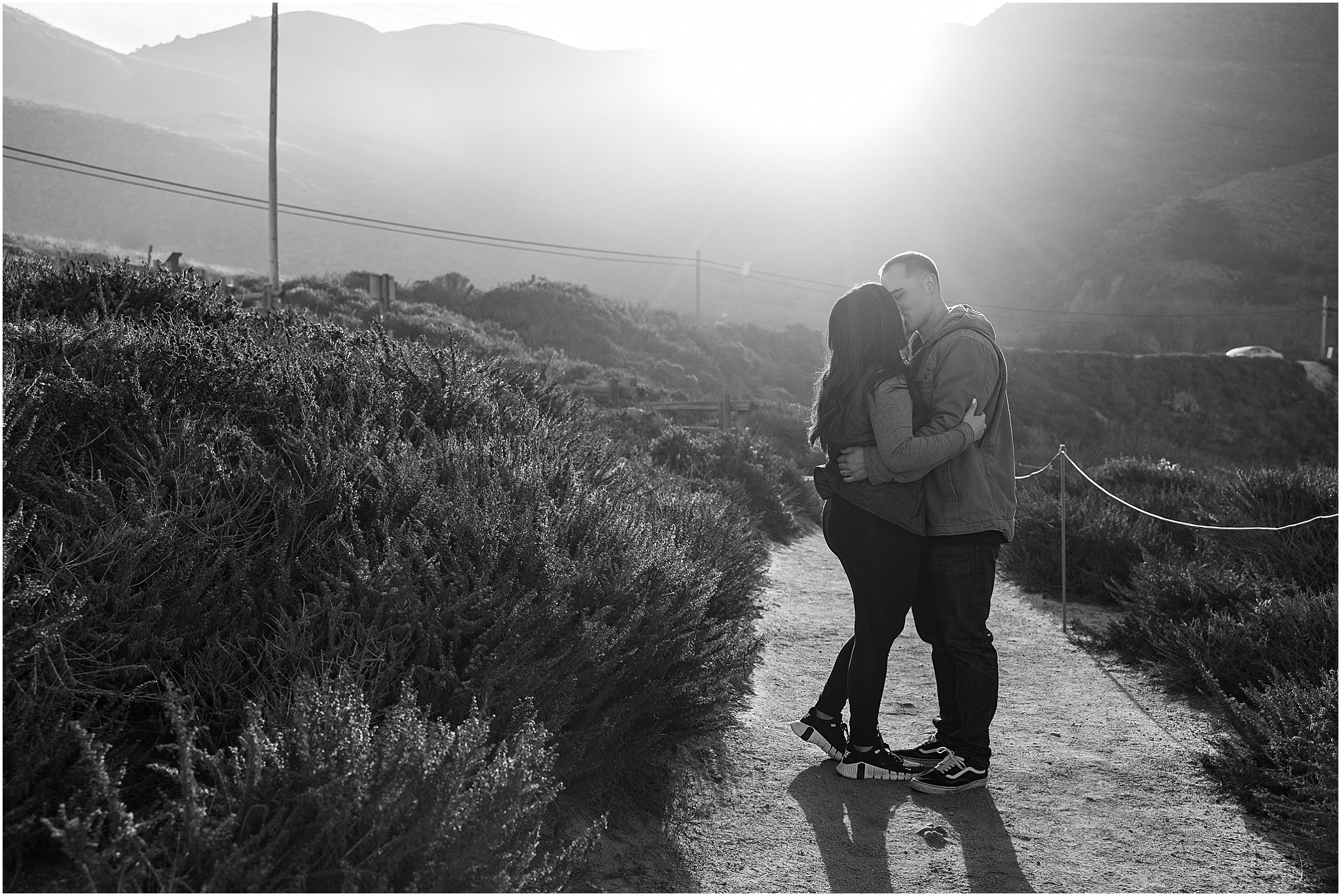Romantic Big Sur kiss with rocky cliffs and ocean.