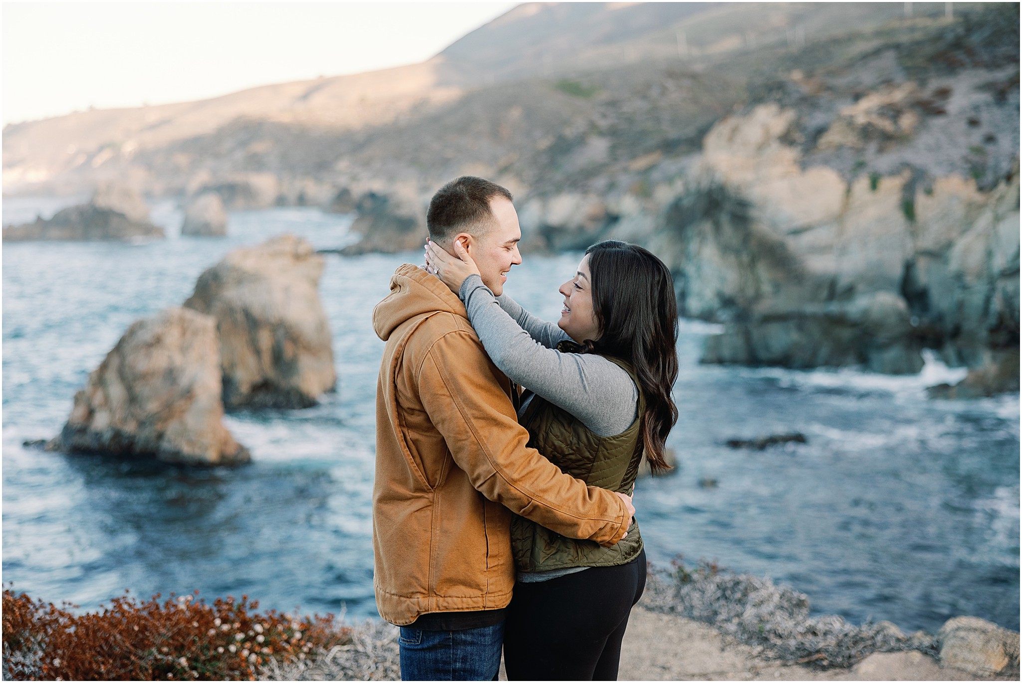 Couple smiling together on cliffside in Big Sur.