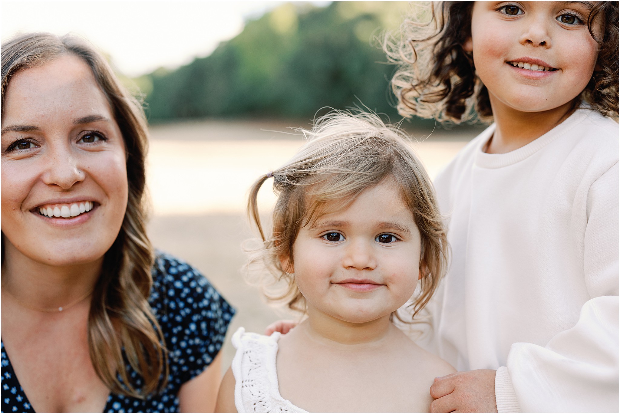 Mom and daughters sharing joyful moment in sunset light.
