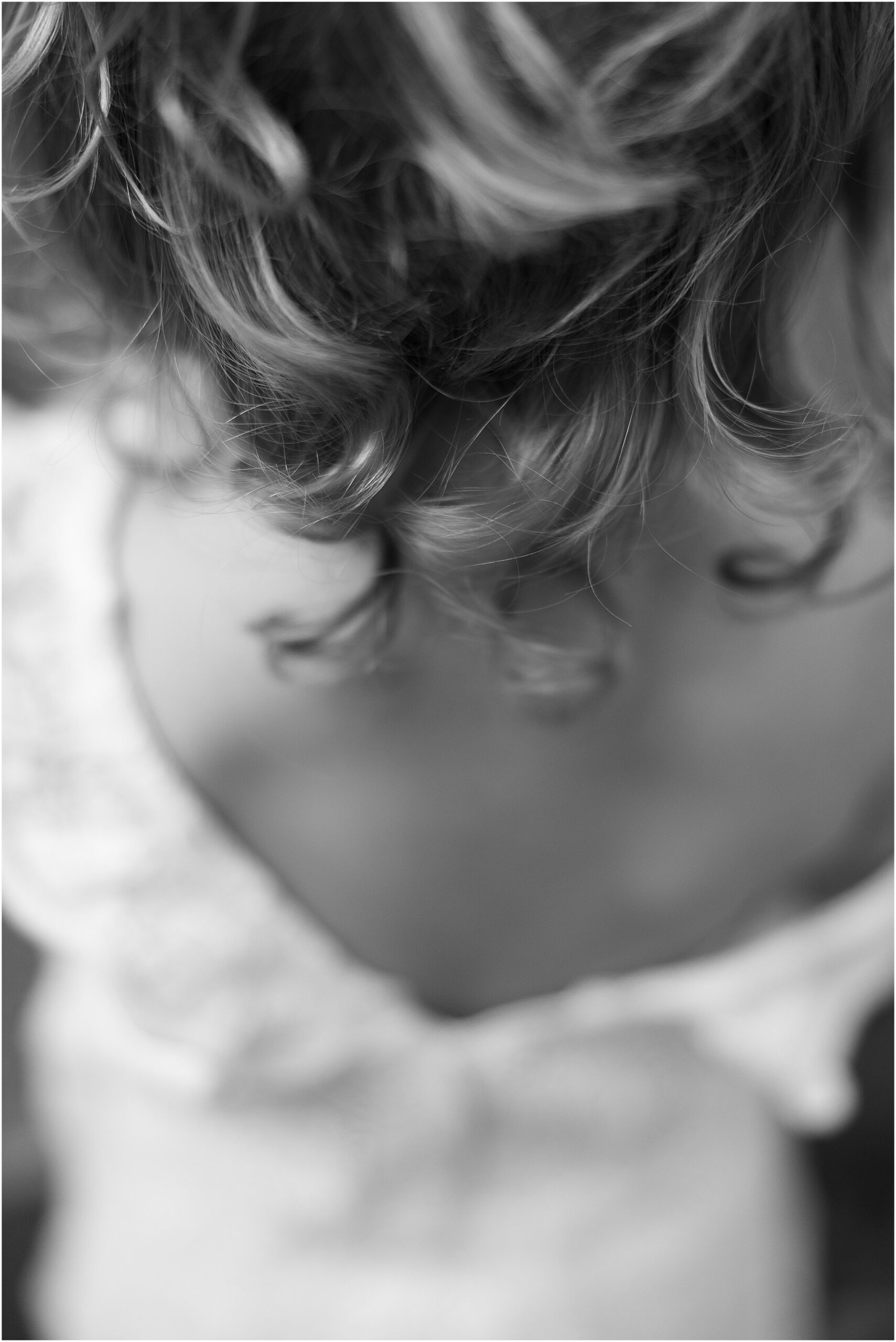 Soft curls glowing in golden hour light as young girl stands in Monterey County field.