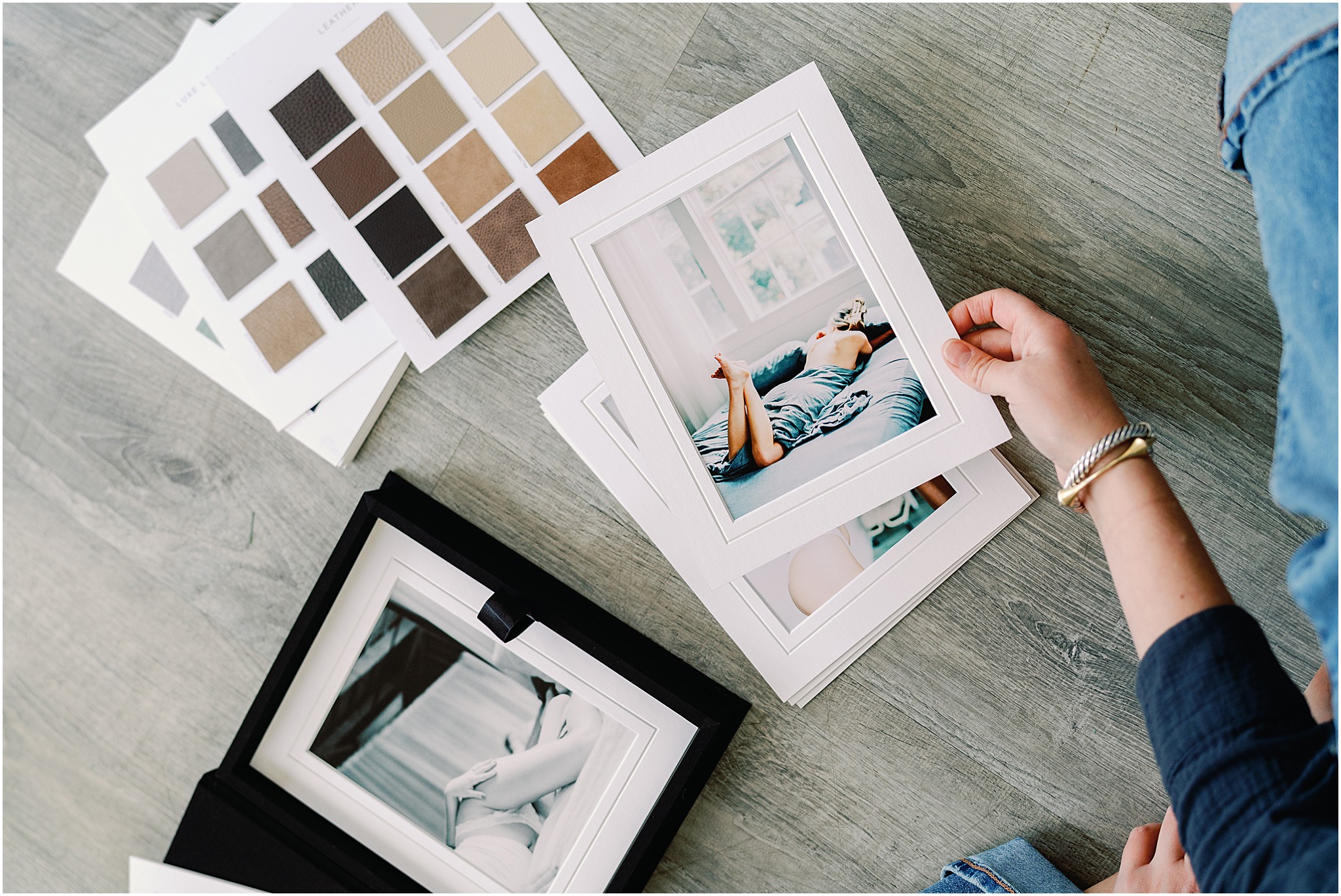 Reviewing boudoir prints alongside material swatches for album customization.