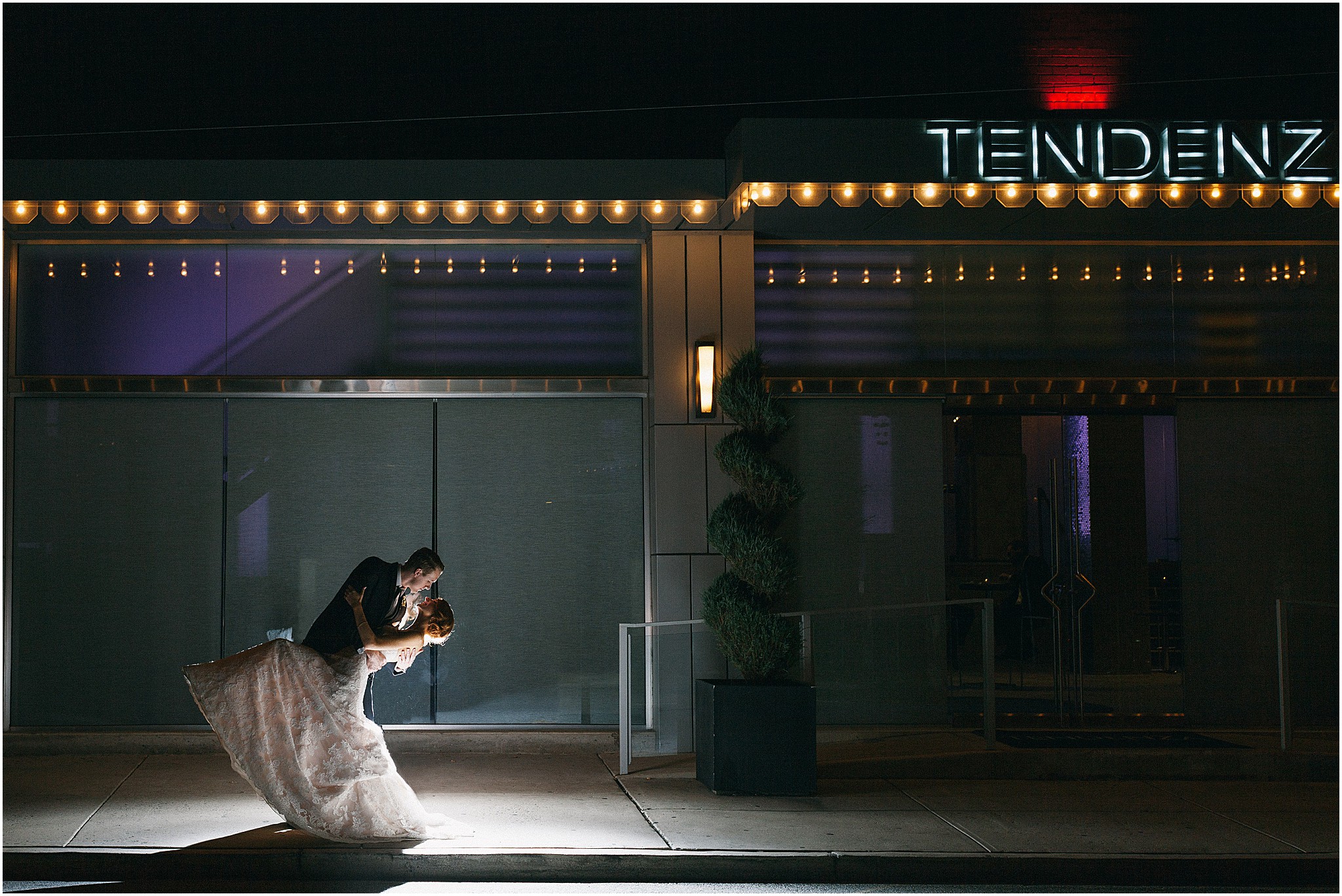 Groom dipping bride for a kiss outside Tendenza wedding venue in Philadelphia at night