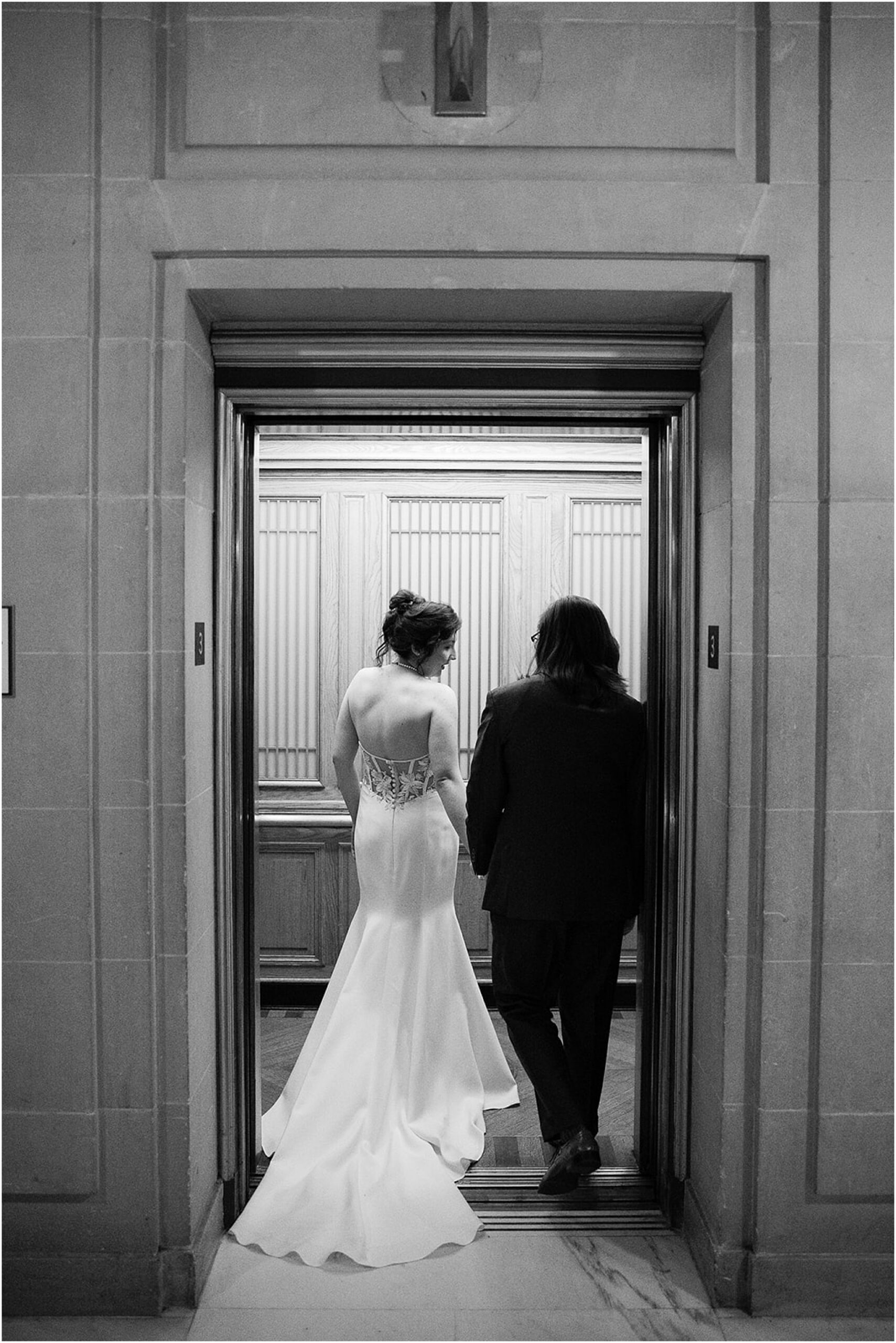 Newlyweds entering elevator together after ceremony.