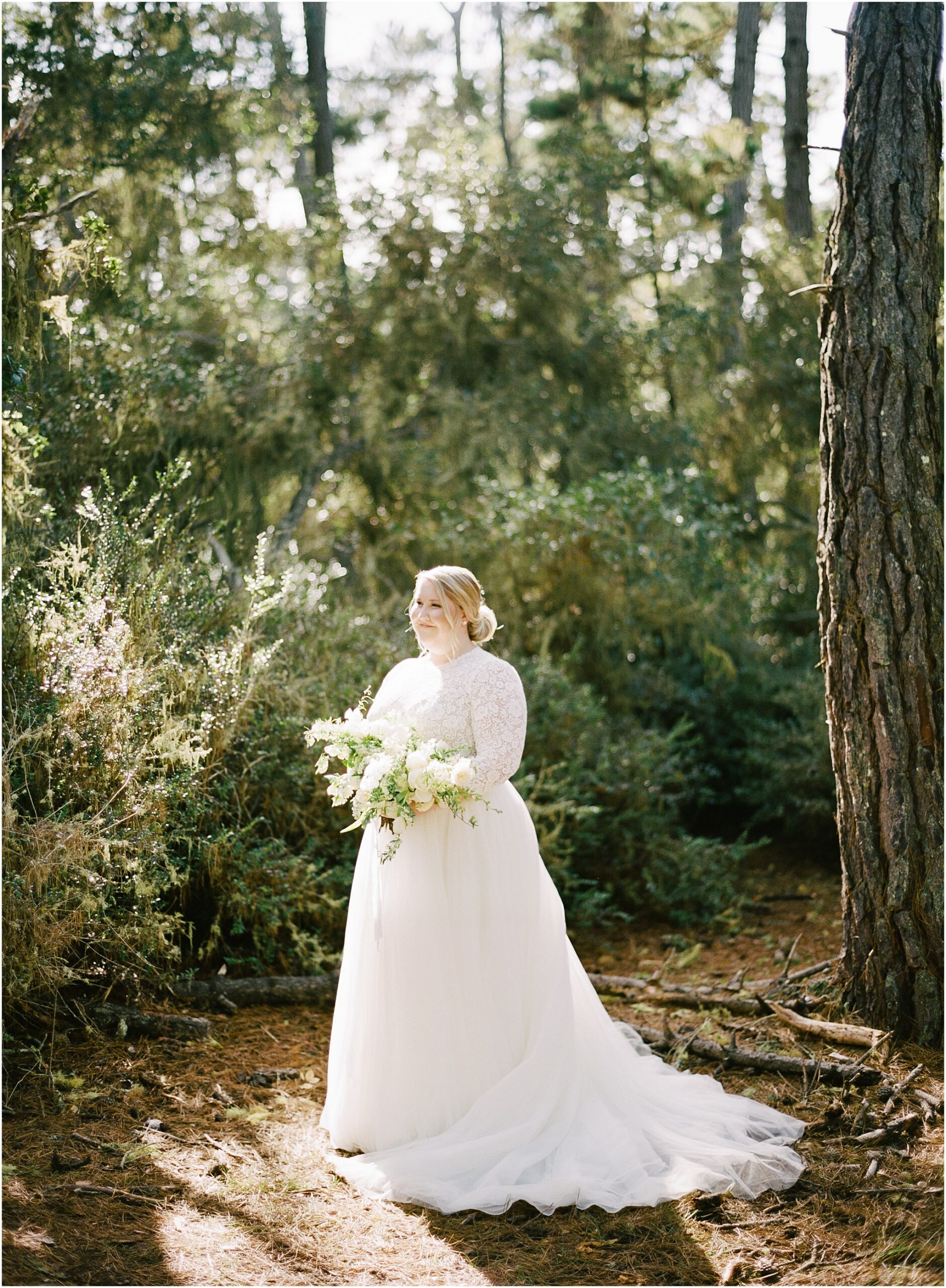 Bride standing in soft light with panoramic Big Sur redwood views.