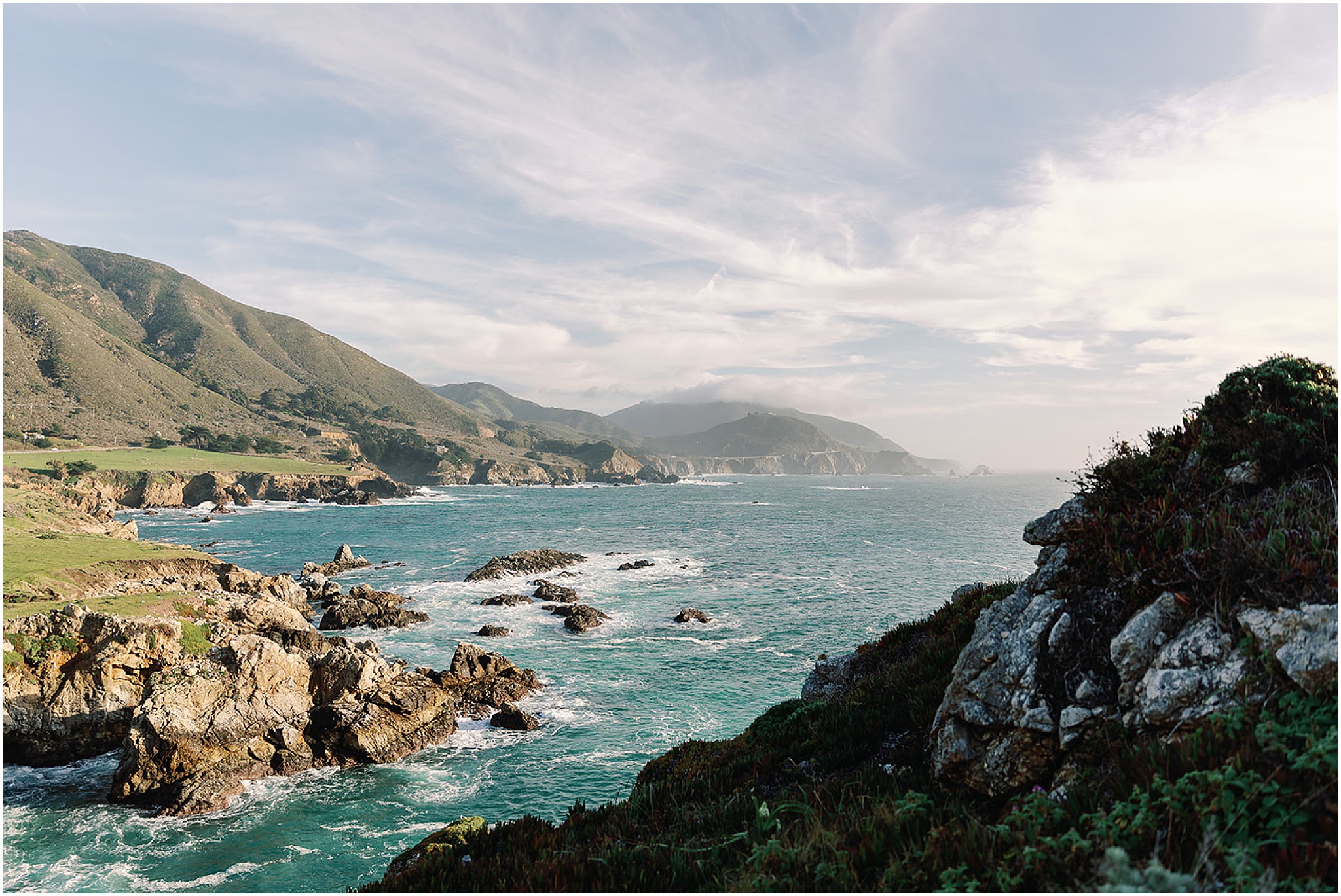Panoramic view of the Big Sur coastline with turquoise water and rocky shoreline.