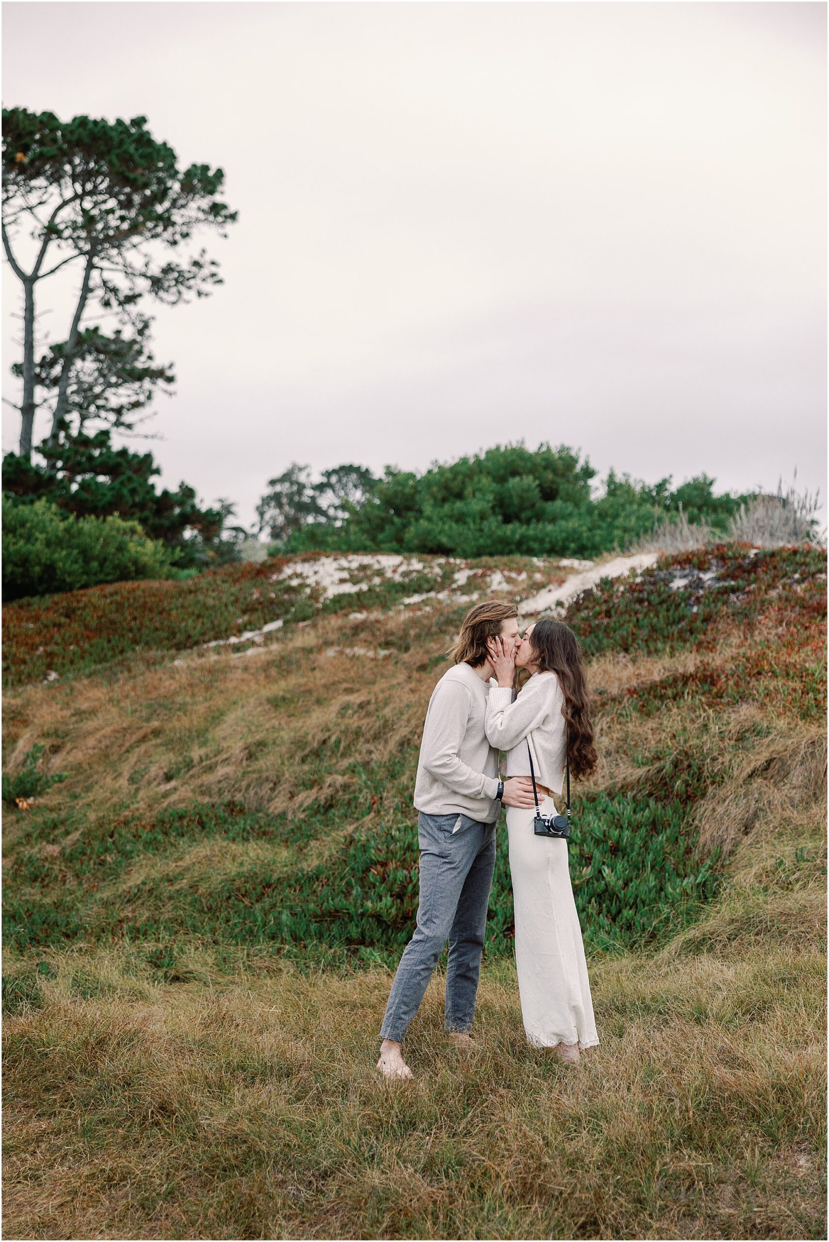 Alex and Connor kissing among the coastal landscape during their Carmel engagement photos