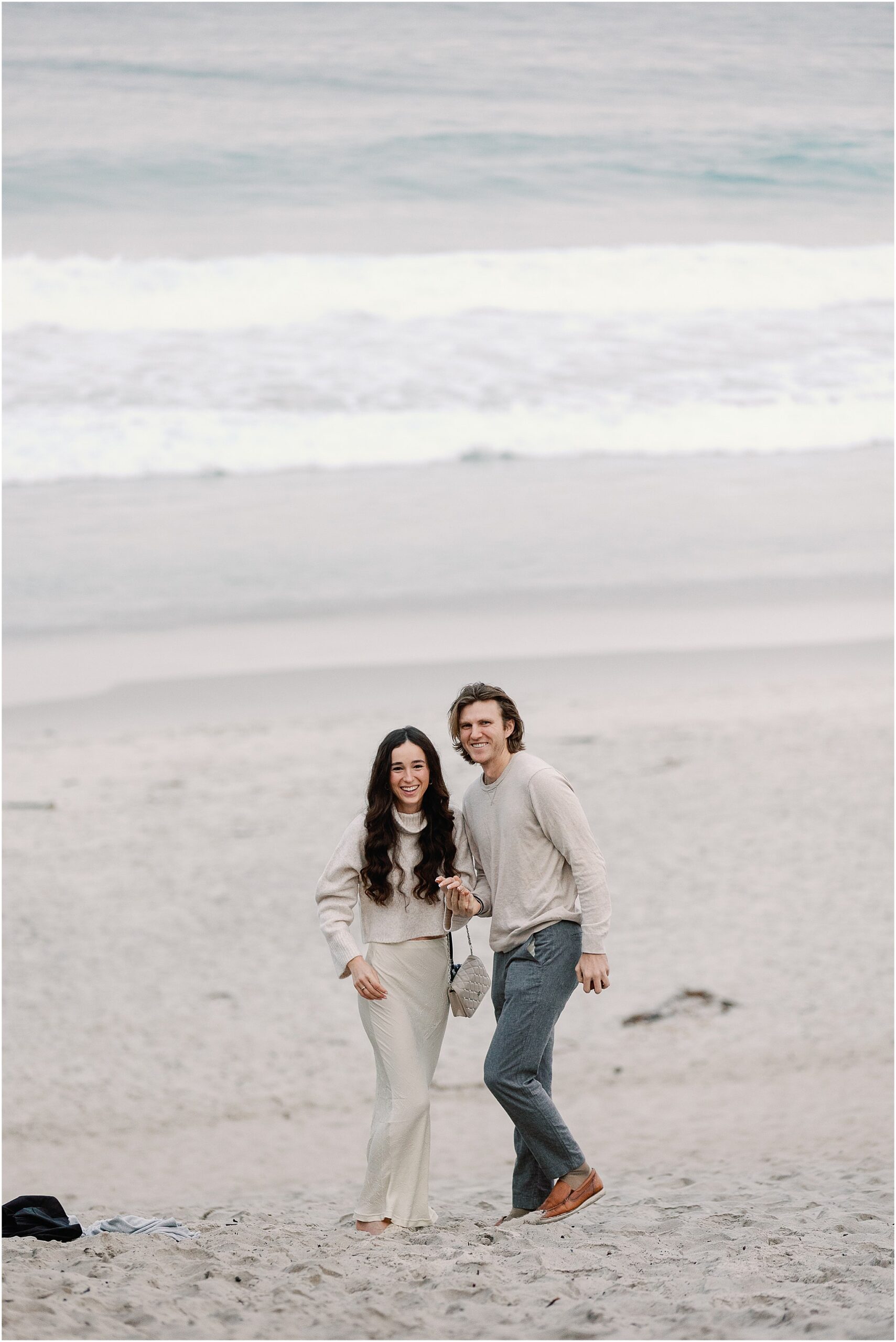 Alex and Connor smiling together moments after their surprise Carmel beach proposal