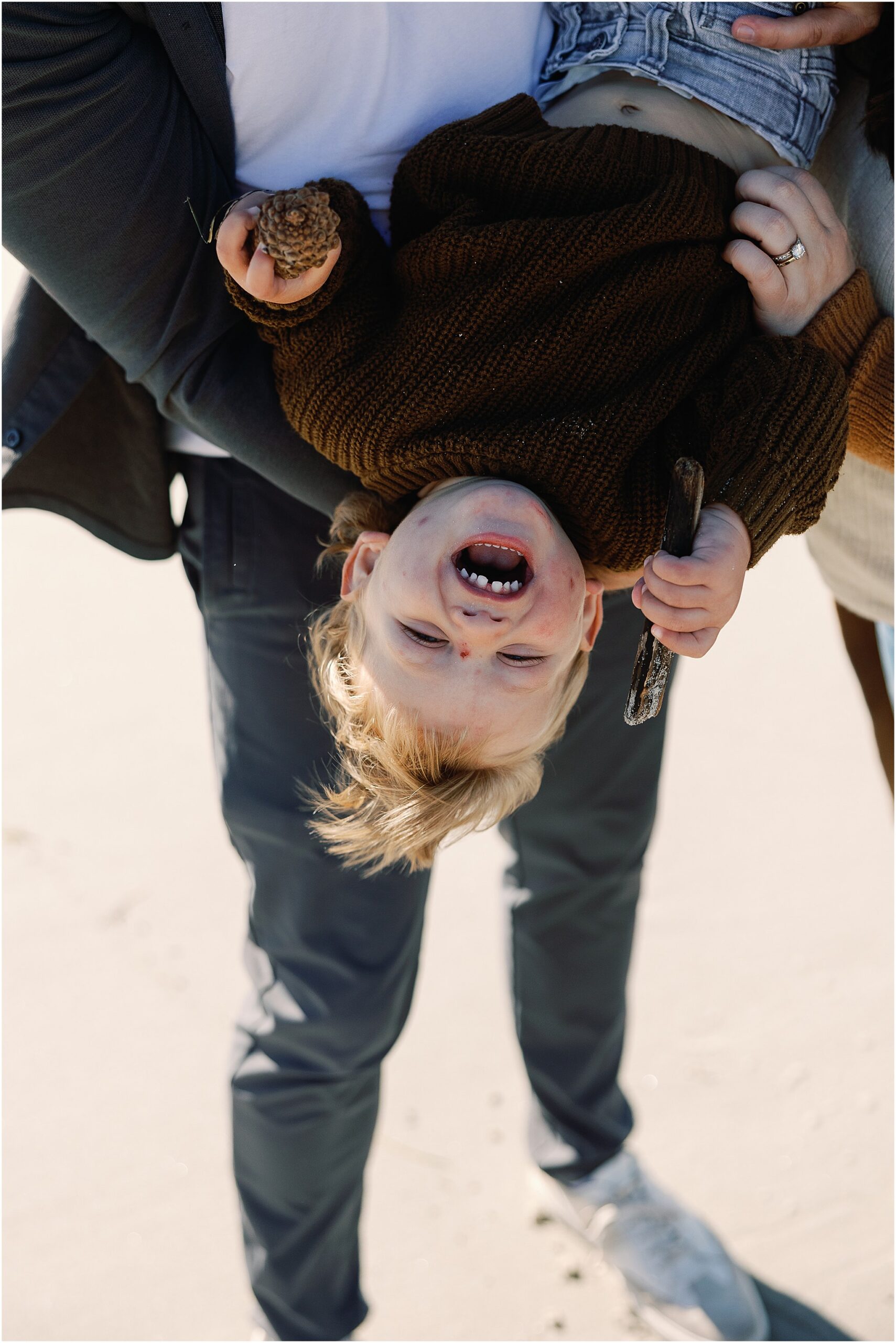 Young child laughing upside down during a playful family photography moment